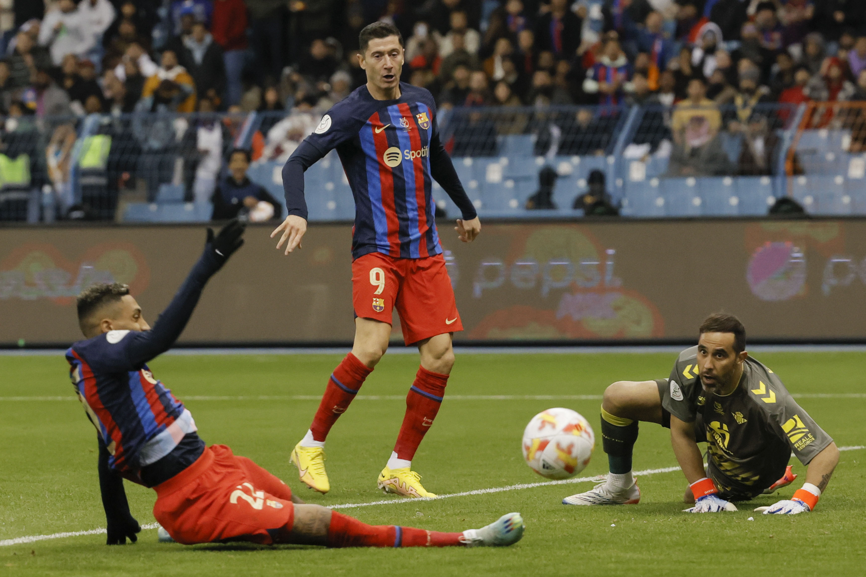 RIAD (ARABIA SAUDÍ), 12/01/2023.-Los jugadores del Barcelona Raphinha (i) y Roberto Lewandowski (c) y el portero del Betis, el chileno Claudio Bravo (d) en el partido de semifinales de la Supercopa de España que enfrenta al Real Betis y al FC Barcelona y que se disputa este jueves en el Estadio Internacional Rey Fahd, en Riad, Arabia Saudí. EFE/ Juan Carlos Cárdenas