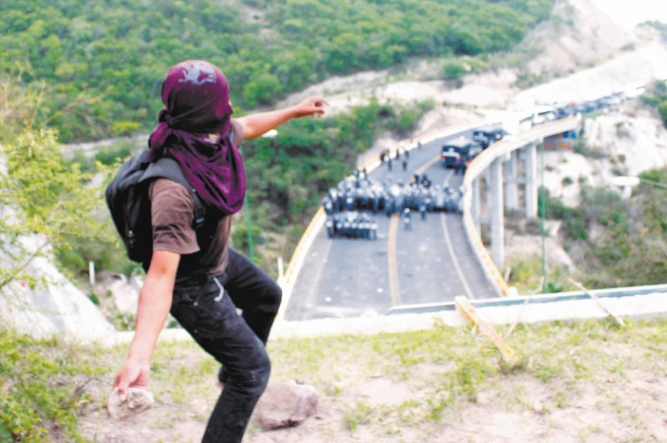 Un manifestante de Ayotzinapa lanza piedras a la policía mexicana que bloqueó una marcha en Chilpancingo-Tixtla. /AFP
