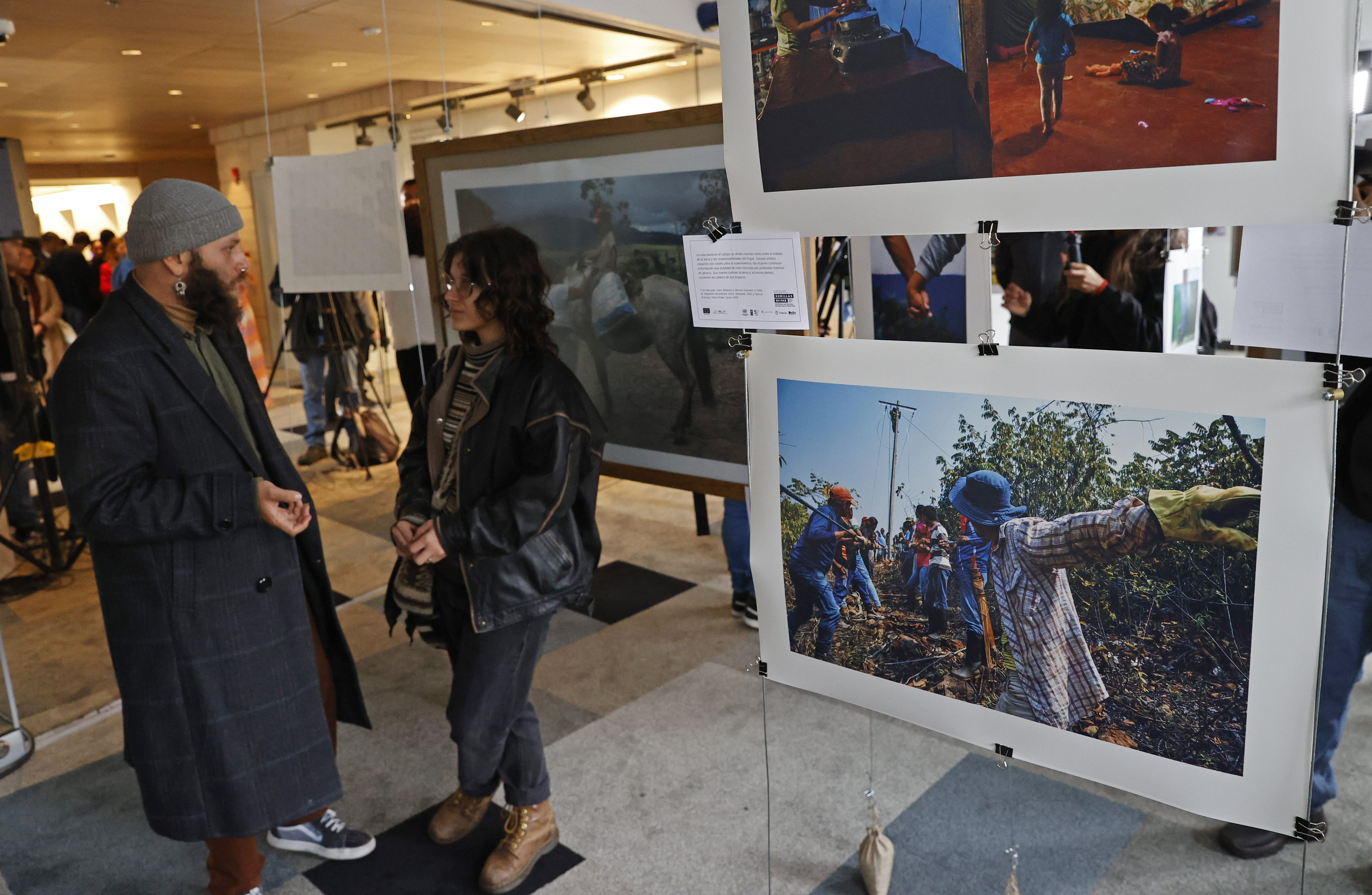 AME3853. BOGOTÁ (COLOMBIA), 30/09/2024.- Personas asisnten a la exposición fotográfica hecha por firmantes de paz este lunes, en Bogotá (Colombia). Rostros heridos por la guerra, con cicatrices, a los que les faltan miembros, pero también rostros atravesados por la paz y la esperanza, de quienes dejaron las armas en la guerrilla de las FARC hace 8 años, forman parte de una exposición fotográfica inaugurada este lunes en Bogotá. EFE/ Mauricio Dueñas Castañeda