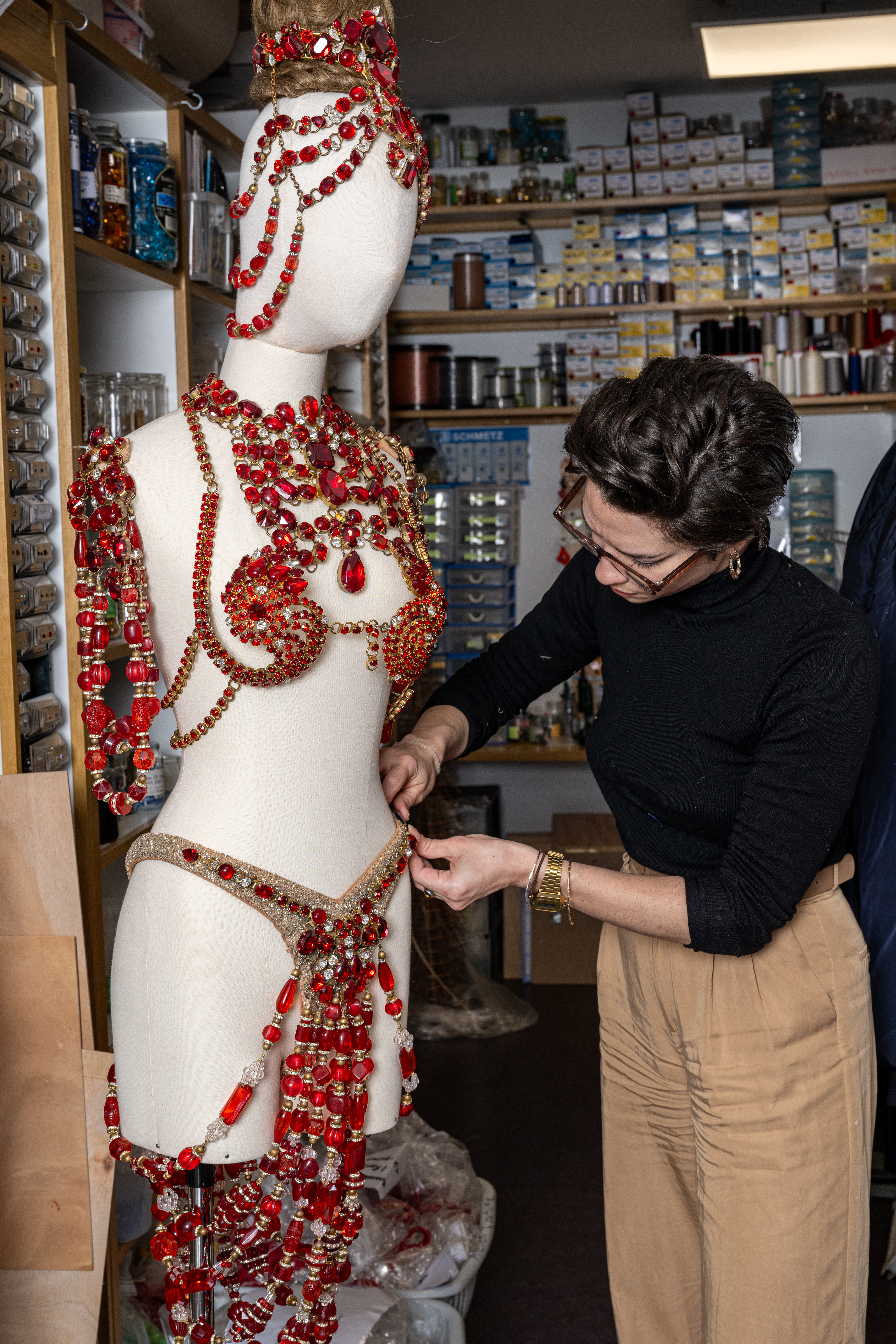 An employee works on a costume bearing rhinestones used by dancers, at the design studio of the Moulin Rouge musical cabaret in Paris on March 13, 2024.