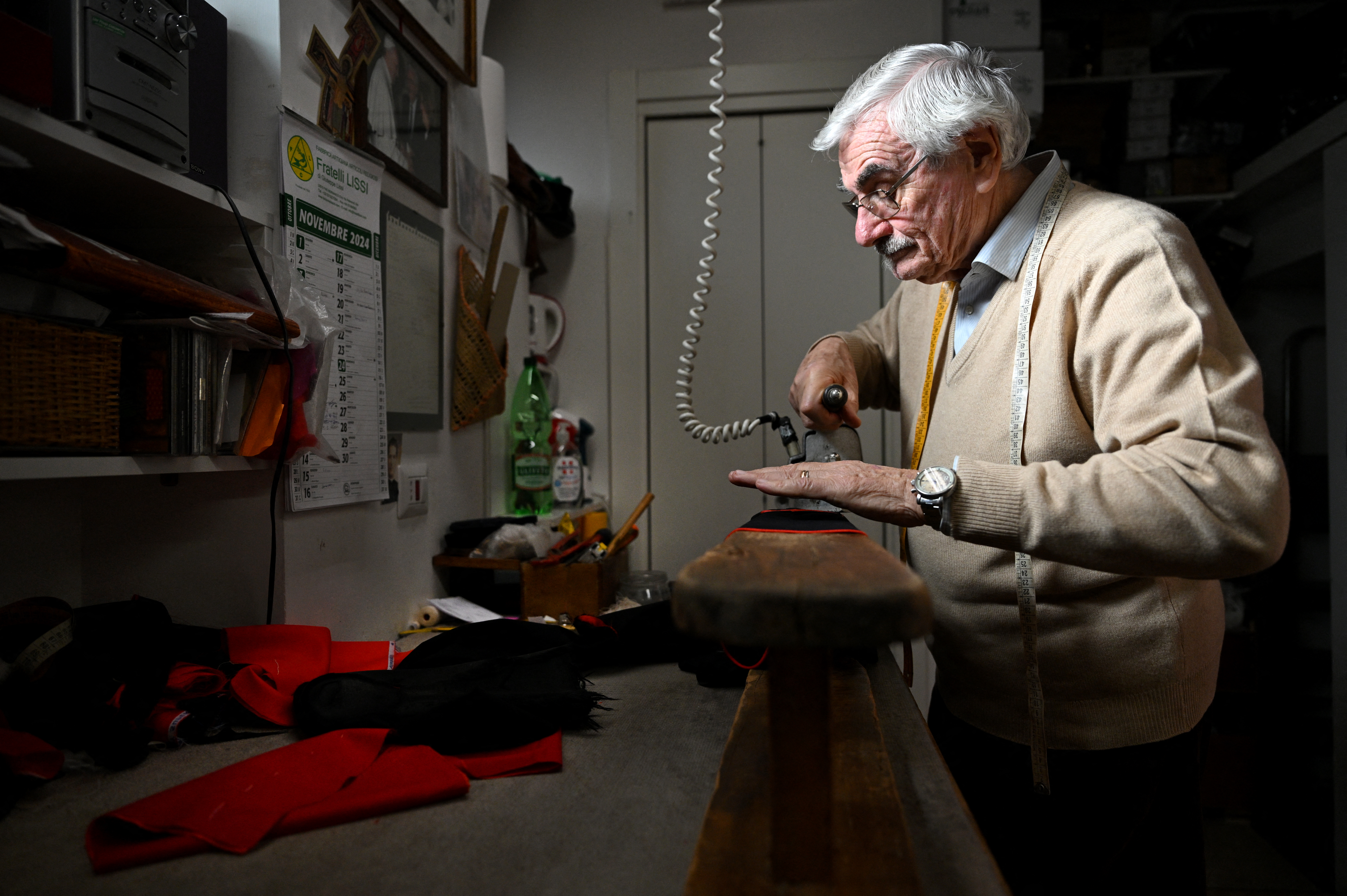 Italian ecclesiastical tailor, Raniero Mancinelli, 86, works on a cardinal's cassock in his shop in Borgo Pio, a neighborhood close to the Vatican, on November 19, 2024 in Rome.