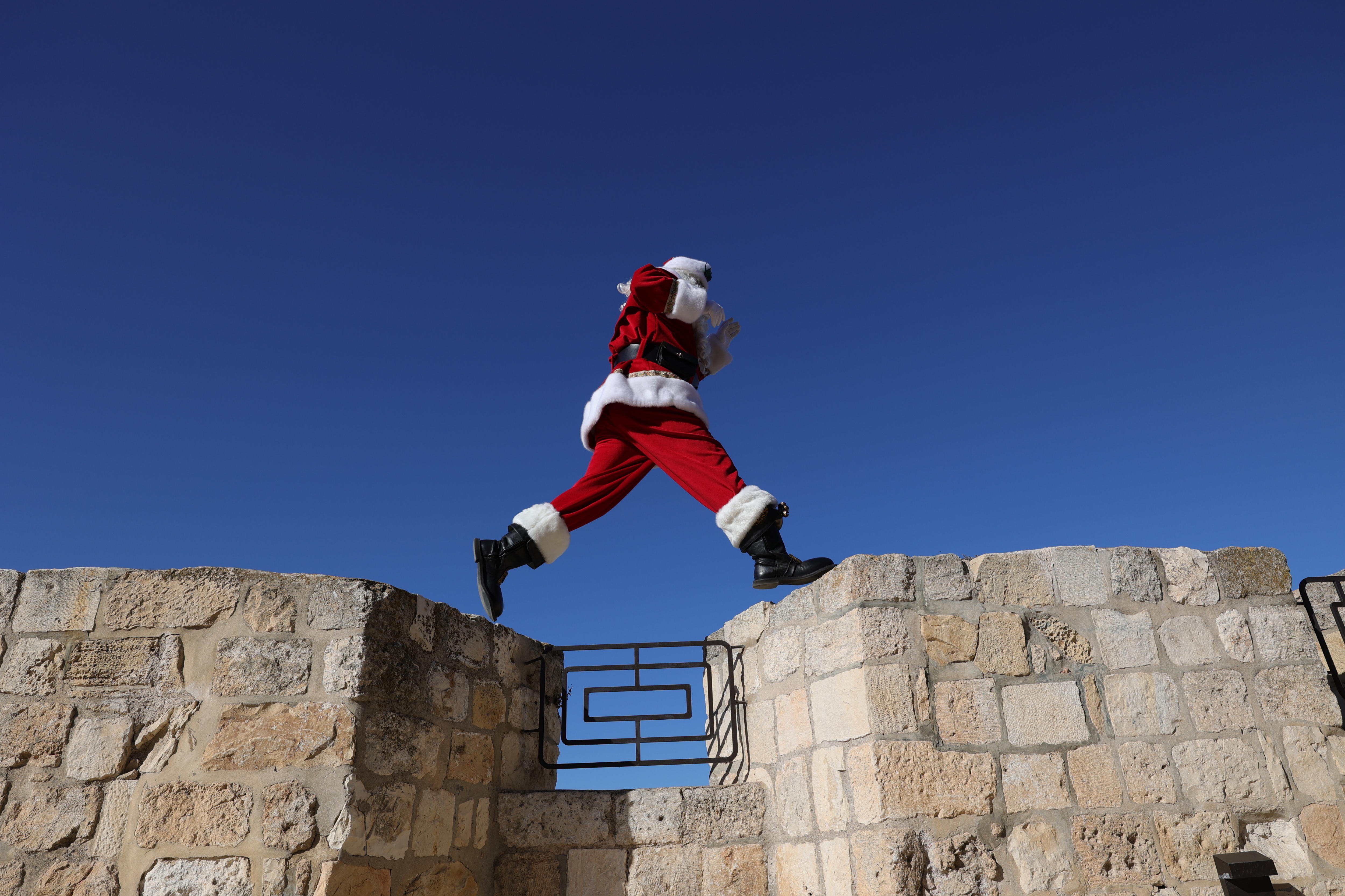 Jerusalem (-), 19/12/2024.- Issa Kassissieh, dressed as Santa Claus, jumps on the old city walls near Jaffa Gate in the Old City of Jerusalem, 19 December 2024, ahead of the Christmas holidays. (Jerusalén) EFE/EPA/ABIR SULTAN
