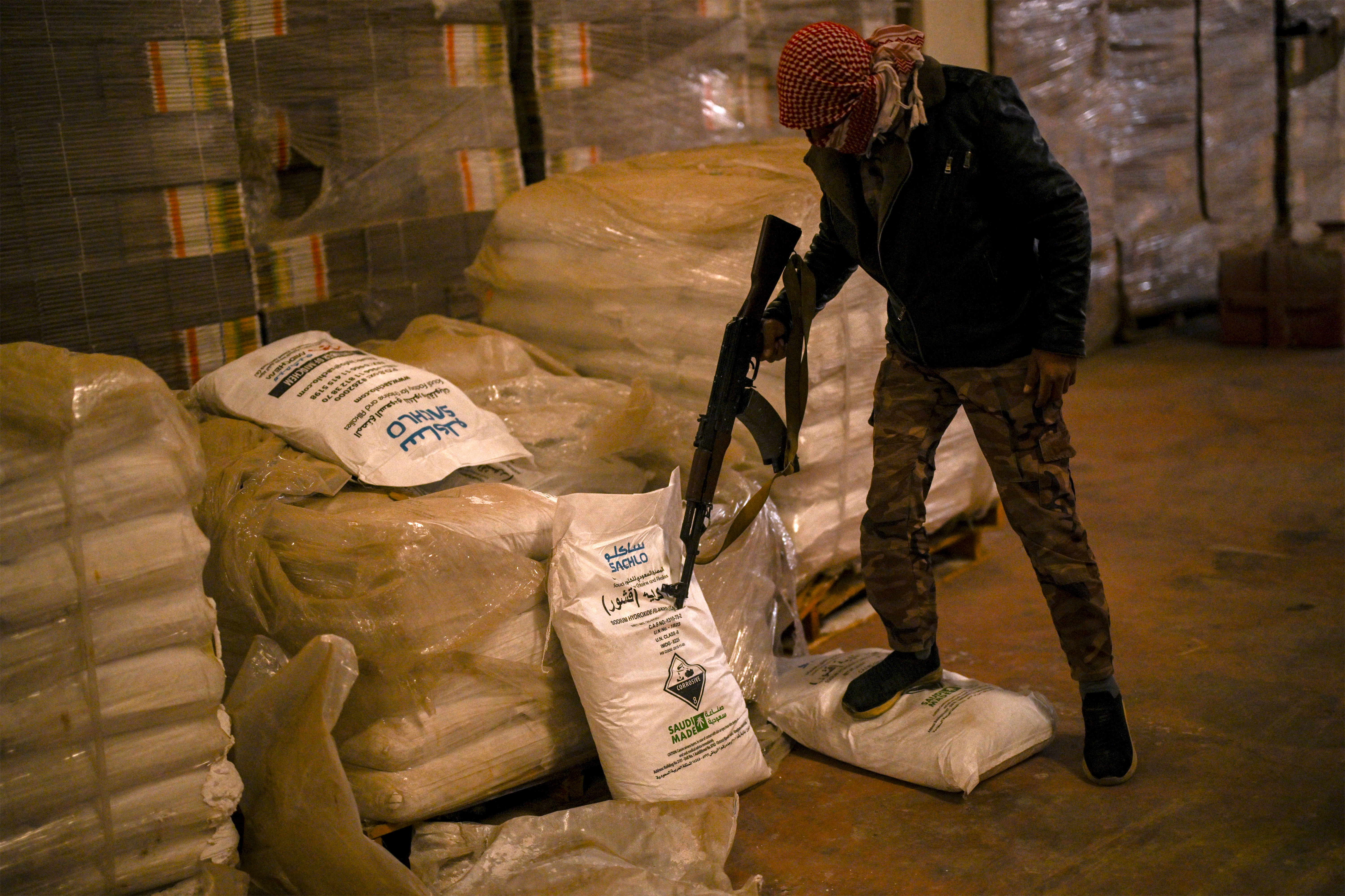 TOPSHOT - Syrian rebel fighters inspect sacks marked to contain "Saudi-made" flakes of caustic soda at a drug manufacturing facility in the city of Douma in the Eastern Ghouta region on the eastern outskirts of Damascus on December 12, 2024.