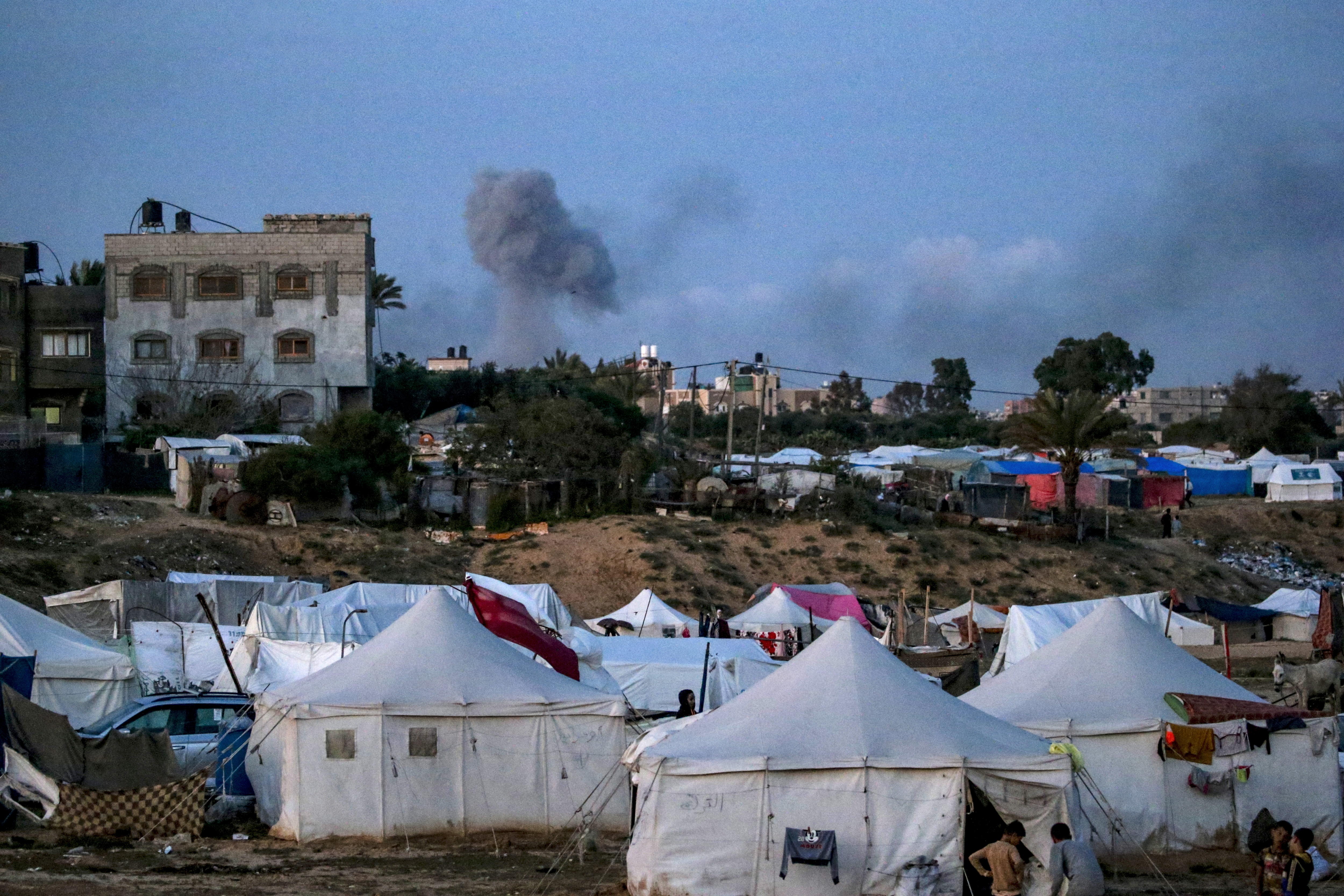 Khan Yunis (Gaza), 11/04/2024.- Vista de los refugios utilizados por las familias palestinas desplazadas que huyeron de sus hogares en el norte de la Franja de Gaza, mientras el humo se eleva al fondo tras los ataques aéreos israelíes en una zona de Khan Yunis,Gaza. EFE/MOHAMMED SABER