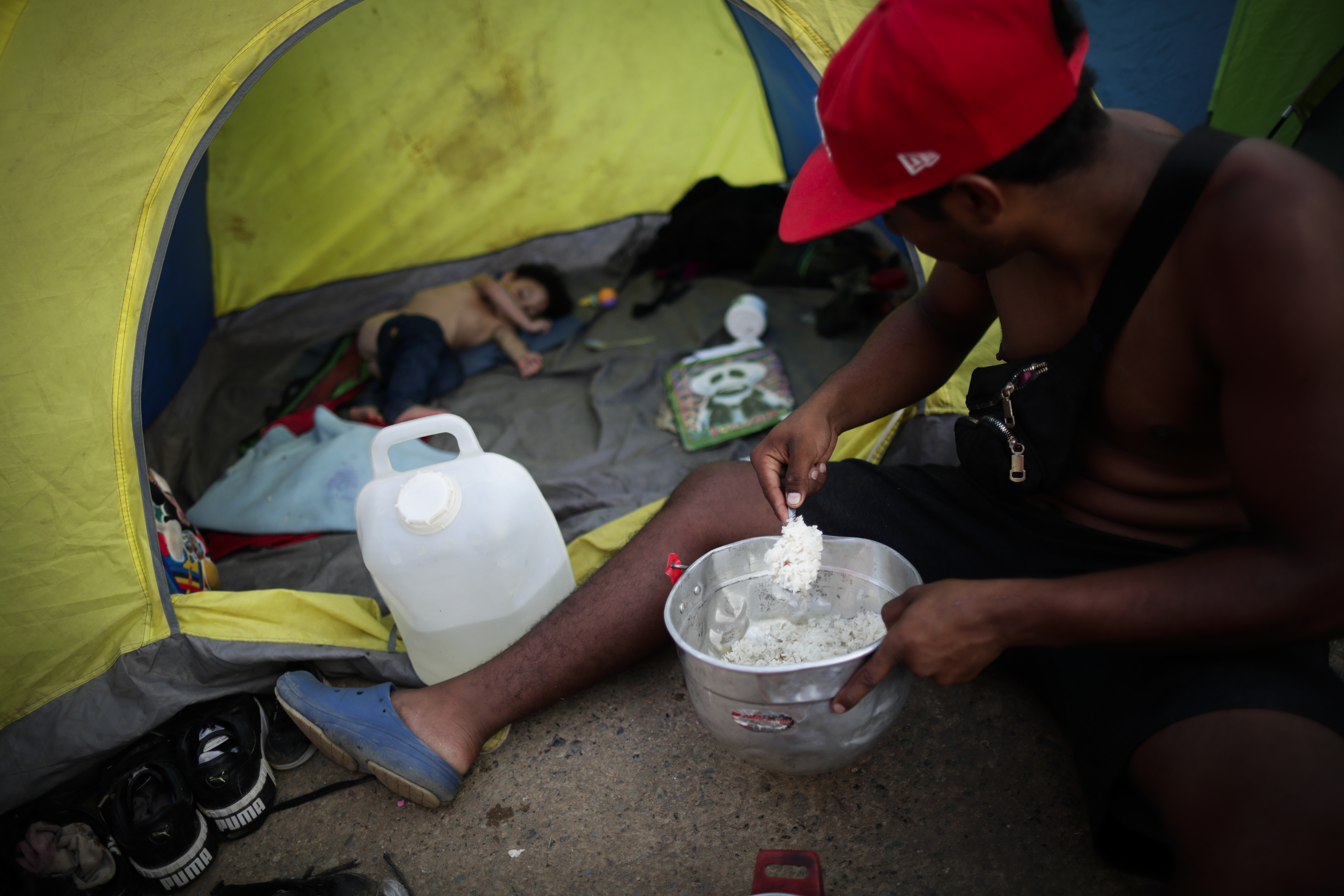 -FOTOGALERÍA- AME4250. BAJO CHIQUITO (PANAMÁ), 21/03/2023.- Yohandry Andrade, un migrante venezolano de 22 años, le sirve comida a su hijo en la comunidad de Bajo Chiquito tras días de caminar por la selva, el 10 de marzo de 2023, en Darién (Panamá). "Guerreros", repiten las madres, hijos guerreros que han aguantado largas caminatas, hambre, sed, el calor, picaduras de insectos, superar ríos y cerros, para sobrevivir a la selva del Darién en su ruta hacia Estados Unidos. Recién salidos de esta selva que hace de frontera natural entre Colombia y Panamá, los migrantes llegan hasta la conocida como Quebrada del León, donde les esperan unas piraguas de indígenas que los descenderán por el casi seco río Tuquesa hasta Bajo Chiquito, una pequeña población emberá donde podrán al fin reposar tranquilos. EFE/ Bienvenido Velasco