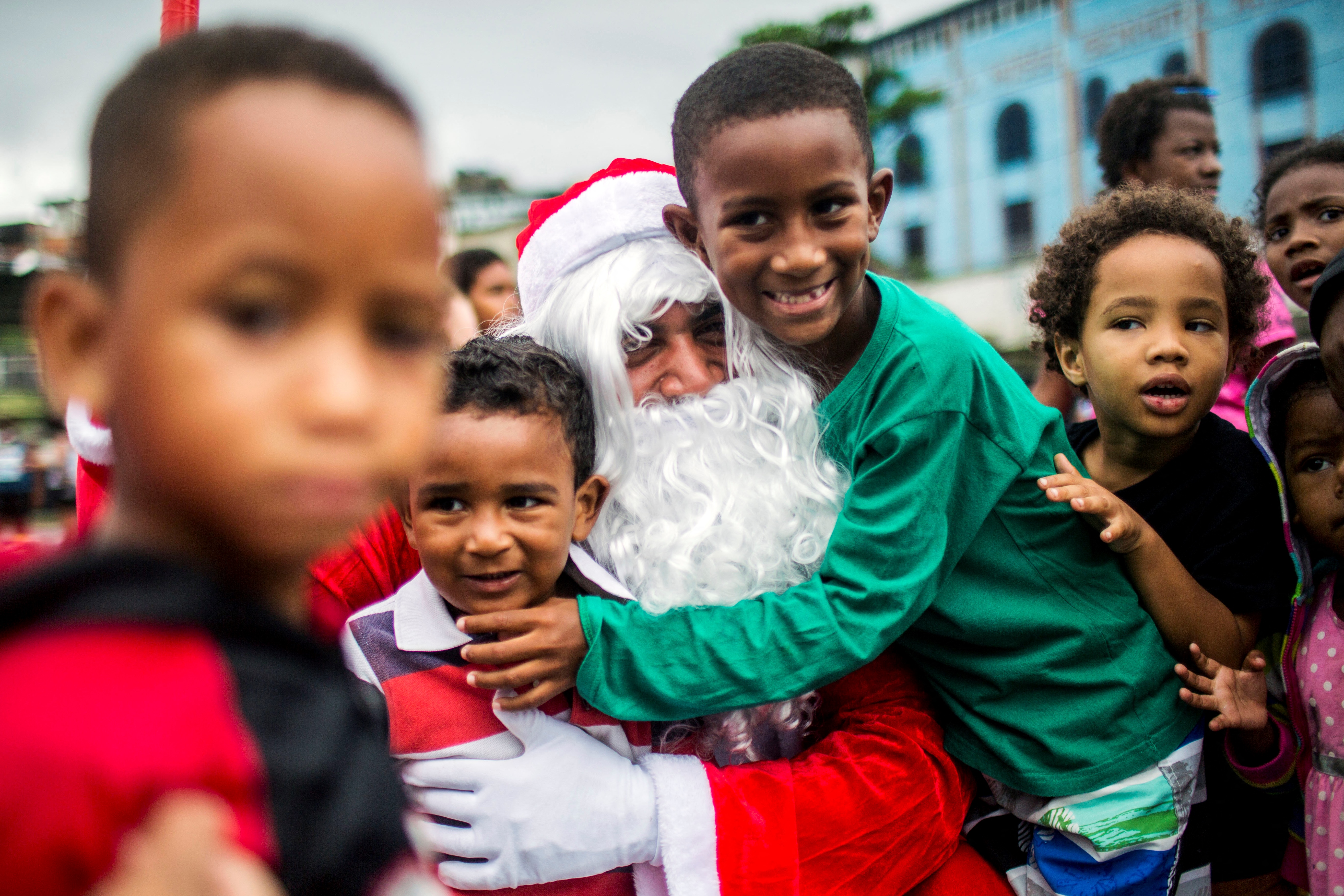 Brasil: Un hombre disfrazado de Papá Noel abraza a los niños durante una distribución de comida navideña organizada por la ONG Central Única das Favelas (CUFA) en el barrio de chabolas del Complejo Penha, comúnmente conocido como Complejo Alemao, en Río de Janeiro.