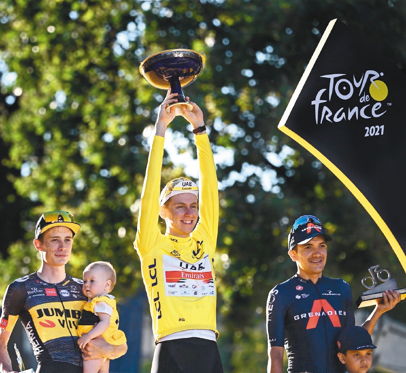 Winner Team UAE Emirates' Tadej Pogacar of Slovenia celebrates with the trophy on the podium at the end of the 21th and last stage of the 108th edition of the Tour de France cycling race, 108 km between Chatou and Paris Champs-Elysees, on July 18, 2021. / AFP / Anne-Christine POUJOULAT