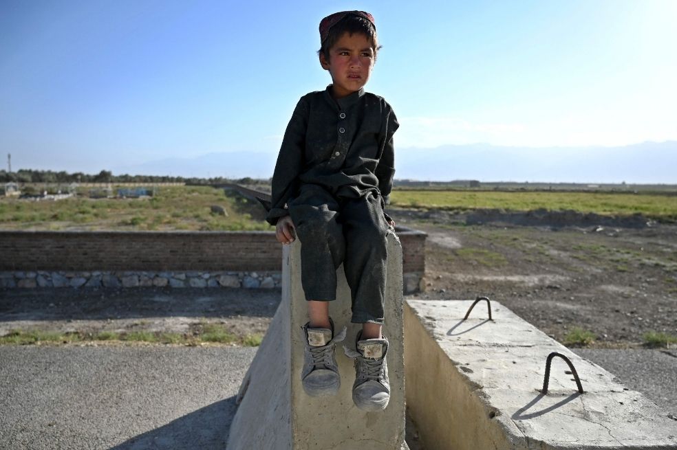 Un niño sentado sobre barreras de cemento a lo largo de una carretera cerca de una base militar estadounidense en Bagram.