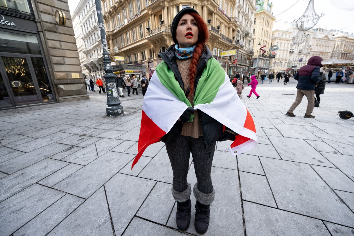 A protester drapped in an Iranian flags attends a demonstration against the Iranian government at Stephansplatz square in Vienna, Austria on January 11, 2026. (Photo by Joe Klamar / AFP)