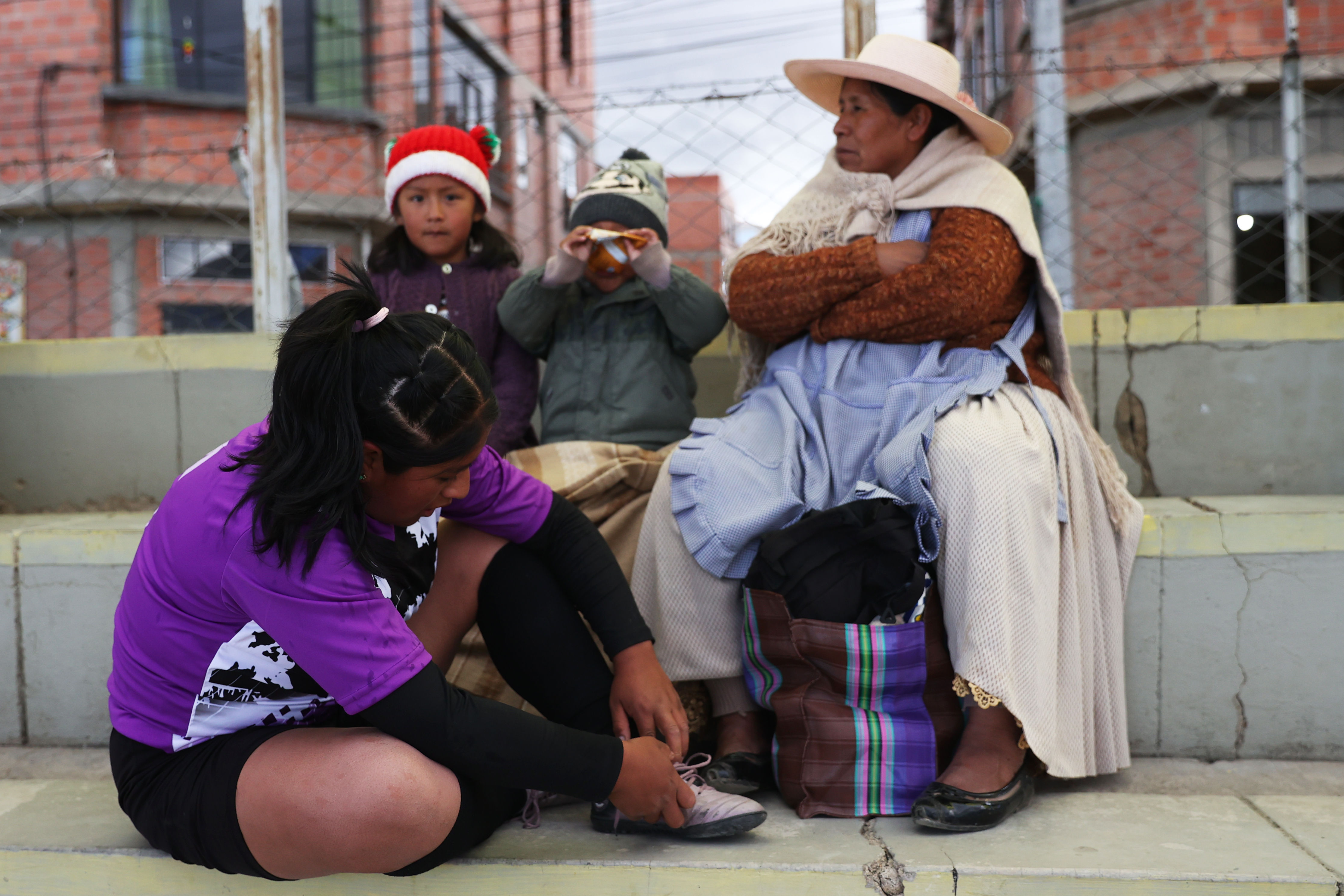 AME029. EL ALTO (BOLIVIA), 19/03/2024.- Una mujer se prepara junto a su familia para jugar fútbol en una escuela creada por mujeres y para mujeres, el 14 de marzo de 2024, en El Alto (Bolivia). La primera escuela de fútbol creada por mujeres y para mujeres de todas las edades en El Alto se ha abierto espacio poco a poco en los 4.150 metros de altitud de esa ciudad boliviana tumbando el mito de que ese deporte es sólo para hombres, que aún persiste en algunos segmentos de la sociedad. EFE/ Luis Gandarillas