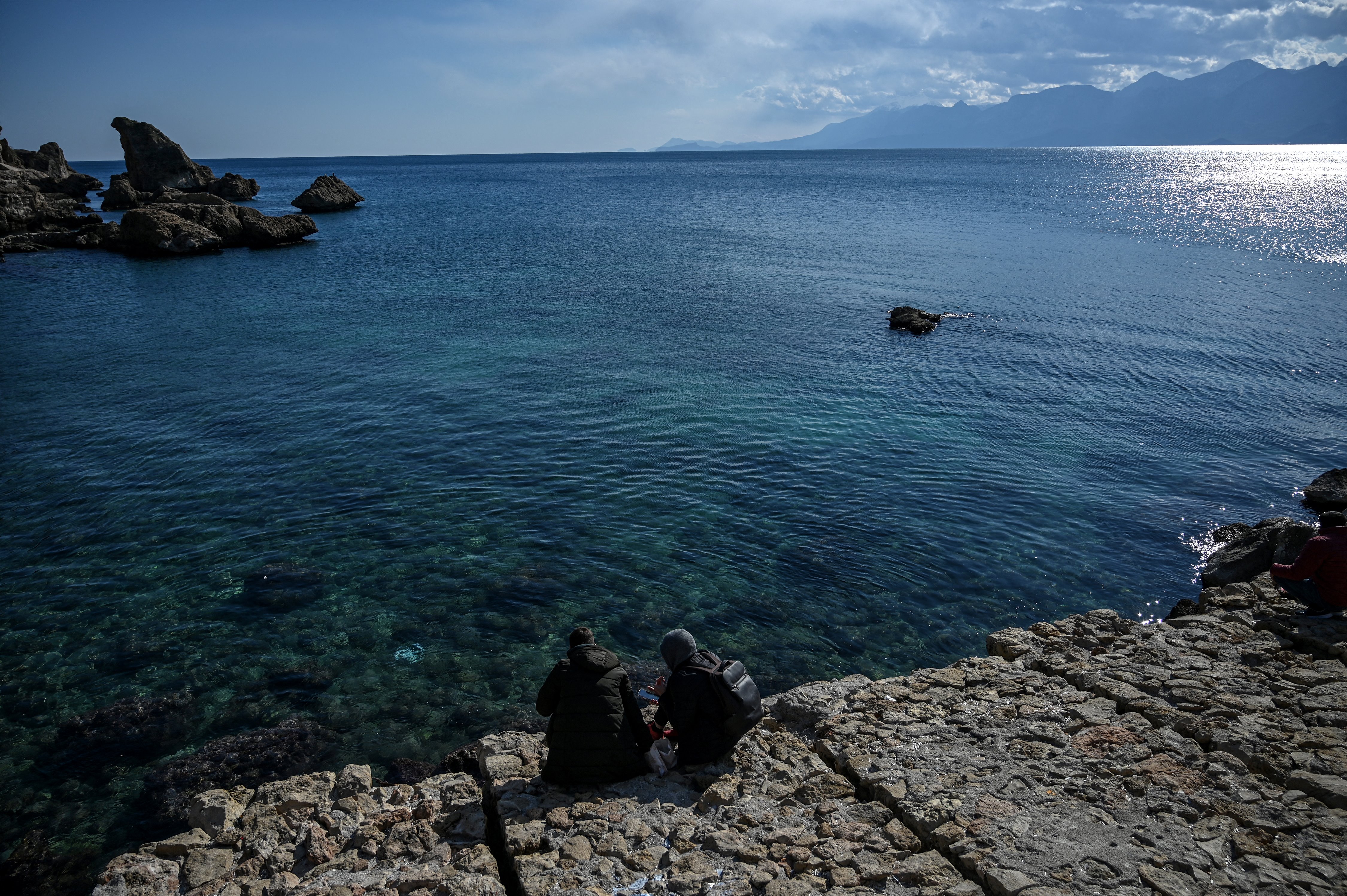 (FILES) Tourist sit by the sea at Kaleici marina in Antalya, in southern Turkey on March 12, 2022.