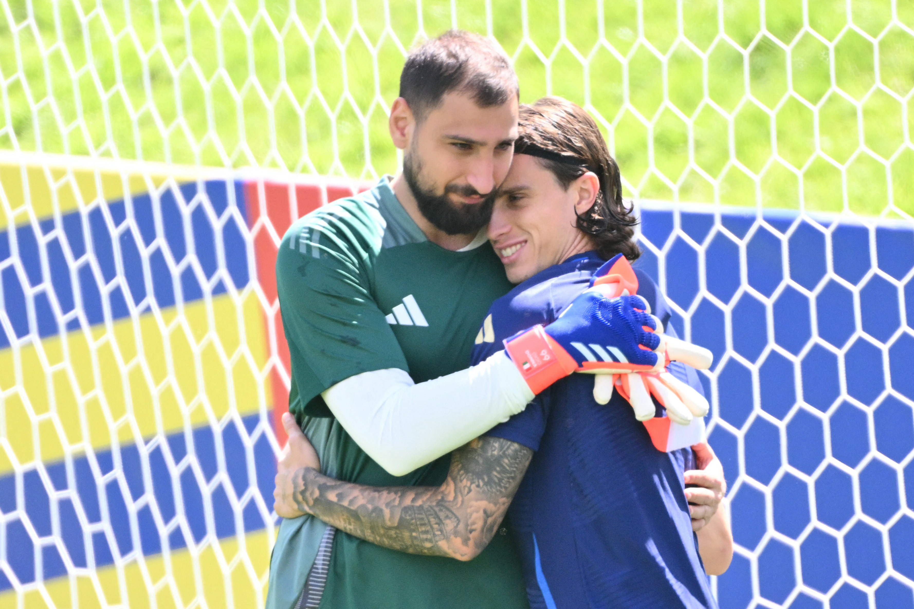 TOPSHOT - Italy's goalkeeper #01 Gianluigi Donnarumma embraces Italy's defender #05 Riccardo Calafiori during an MD-1 training session at the base camp in Iserlohn on June 28, 2024, on the eve of their UEFA Euro 2024 Round of 16 football match against Switzerland.