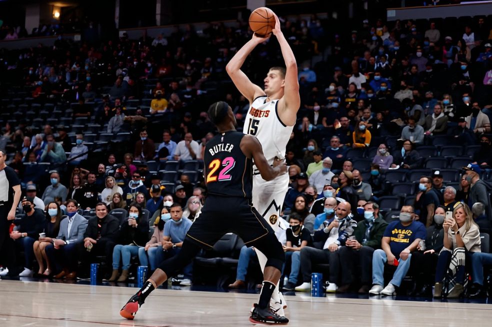 Jimmy Butler (izq.), figura de Miami Heat, marca a Nikola Jokic, estrella de Denver Nuggets.