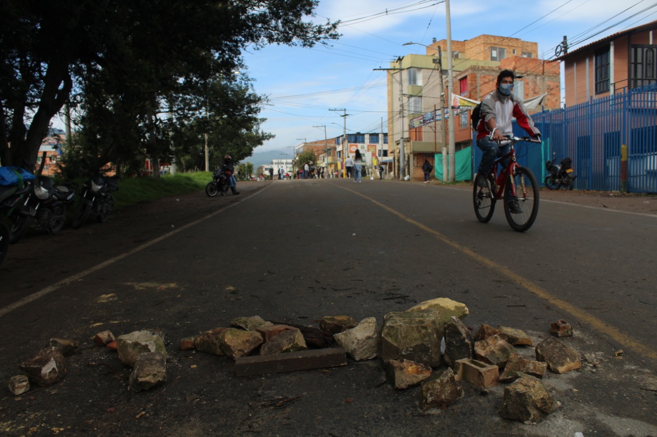 Una persona en bicicleta pasa al lado de varias piedras que dejaron sobre la vía.