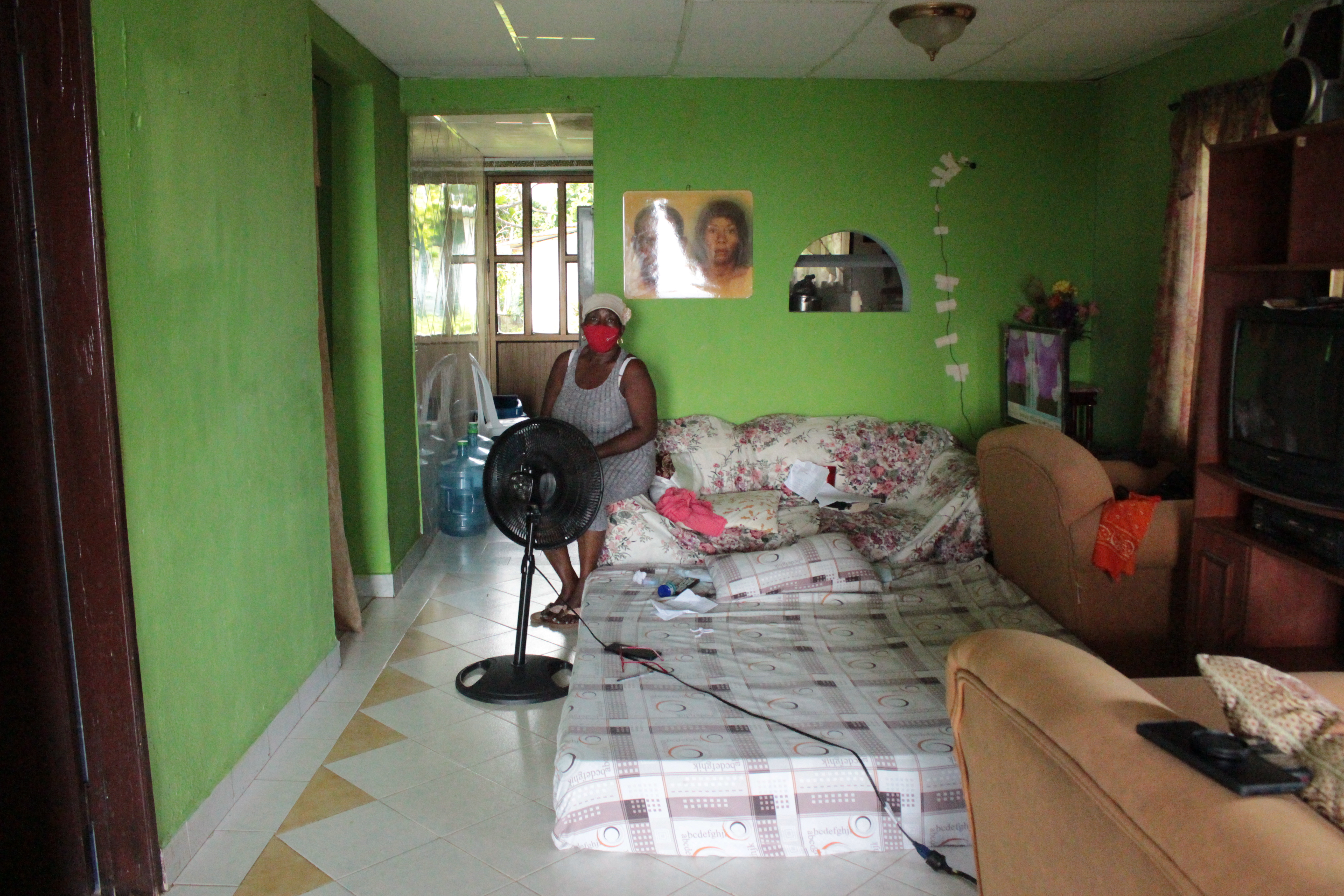 La casa de Erminda Baldonado tiene tres habitaciones, una no tiene techo y está desocupada, en otra tiene sus cosas arrumadas y en la última duerme su esposo que tiene cáncer y está en un tratamiento que requiere que tenga un espacio separado en la casa. Por eso ella duerme en la sala.