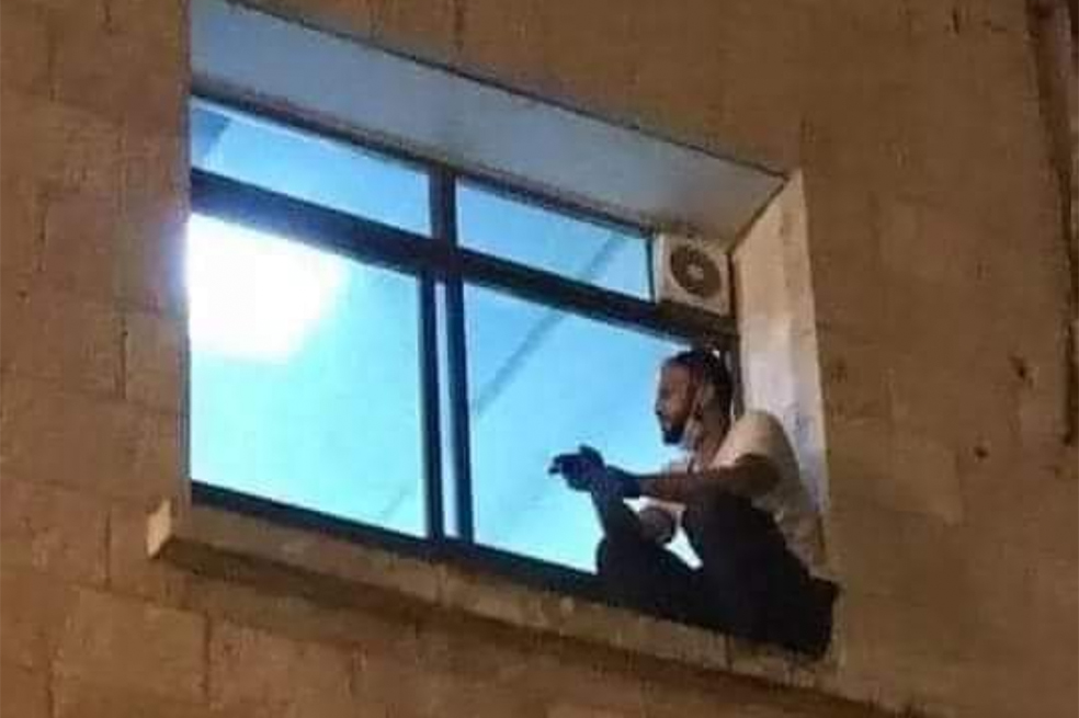 Un joven se despide desde una ventana de su madre internada en una UCI