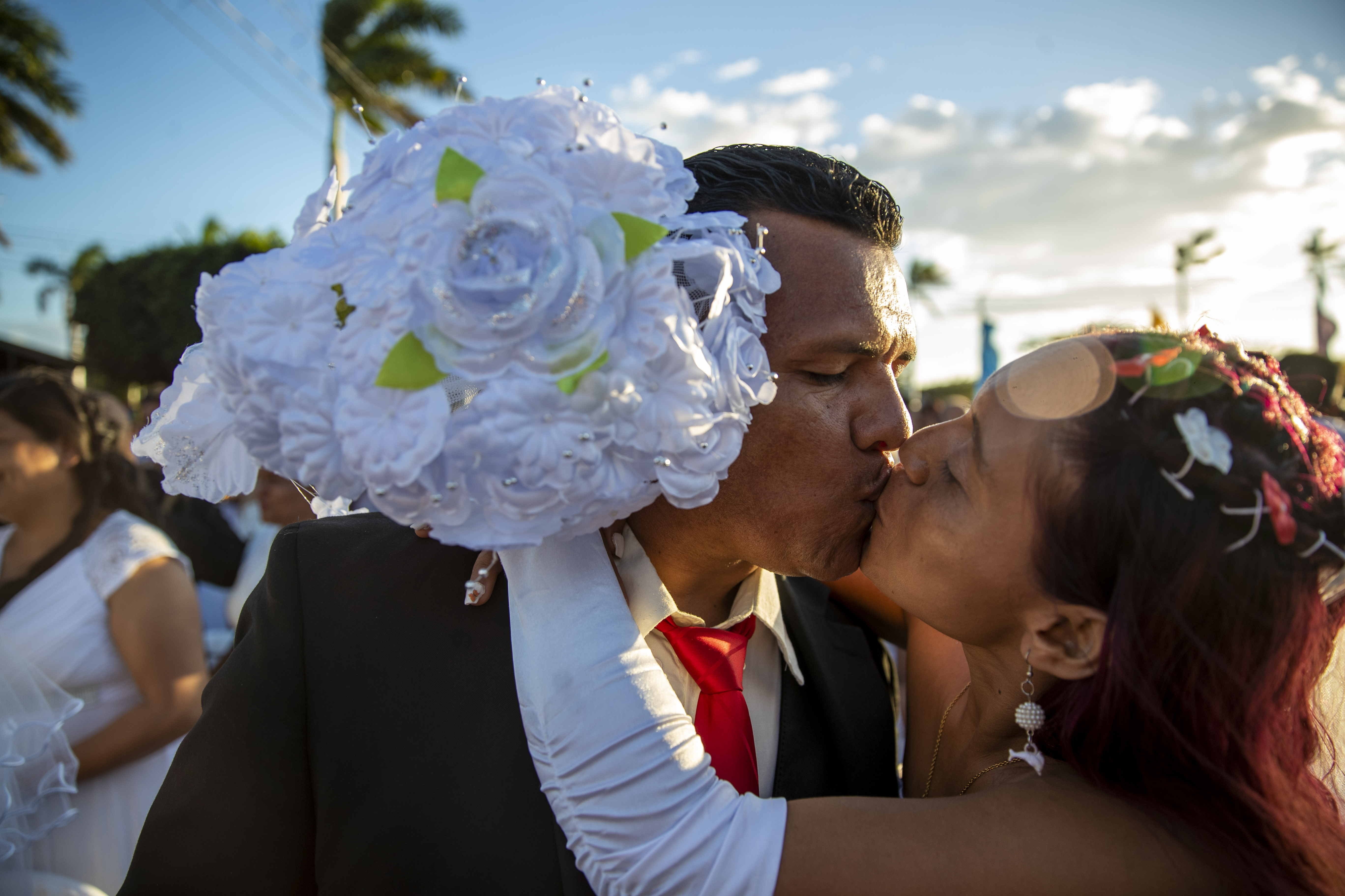 AME5710. MANAGUA (NICARAGUA), 14/02/2022.- Una pareja se besa luego de participar en la celebración de una boda masiva como parte de la celebración del Día de San Valentín, hoy en Managua (Nicaragua). Las parejas contrajeron matrimonio por lo civil en el Parque Japonés, cerca del centro de Managua, en un evento a puertas cerradas que sirvió de preparación legal para la boda eclesiástica masiva, que cada año une la vida de cientos de personas en Nicaragua. Las firmas de los matrimonios fueron celebradas de forma gratuita con el apoyo de la Corte Suprema de Justicia, tal como ha ocurrido en años anteriores, indicó la radioemisora Nueva Radio Ya, que organiza el evento. EFE/ Jorge Torres