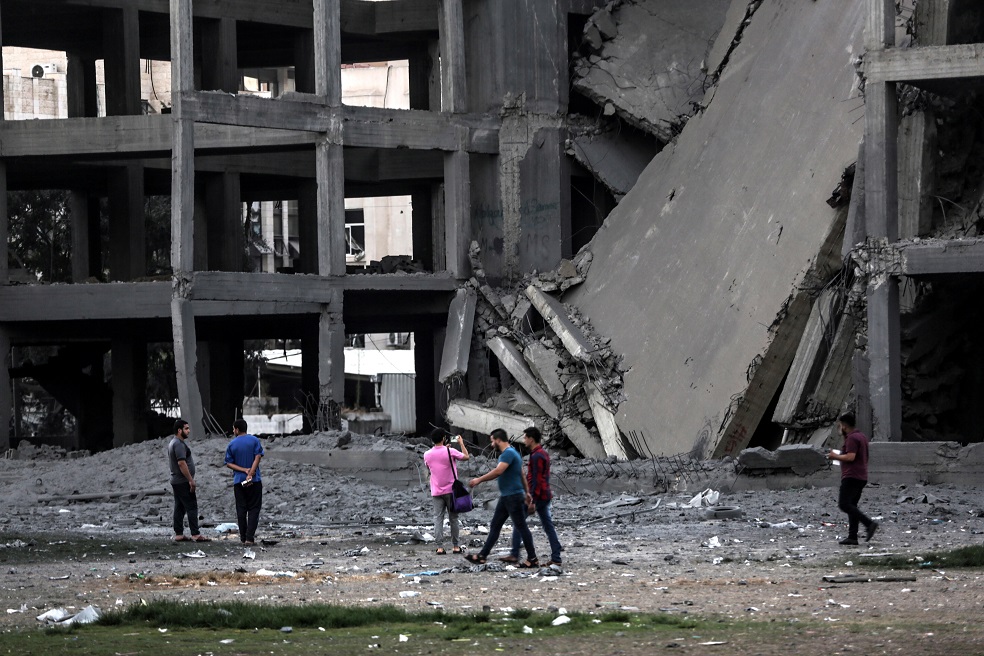 Palestinos caminando cerca a uno de los edificios bombardeados por Israel  / EFE