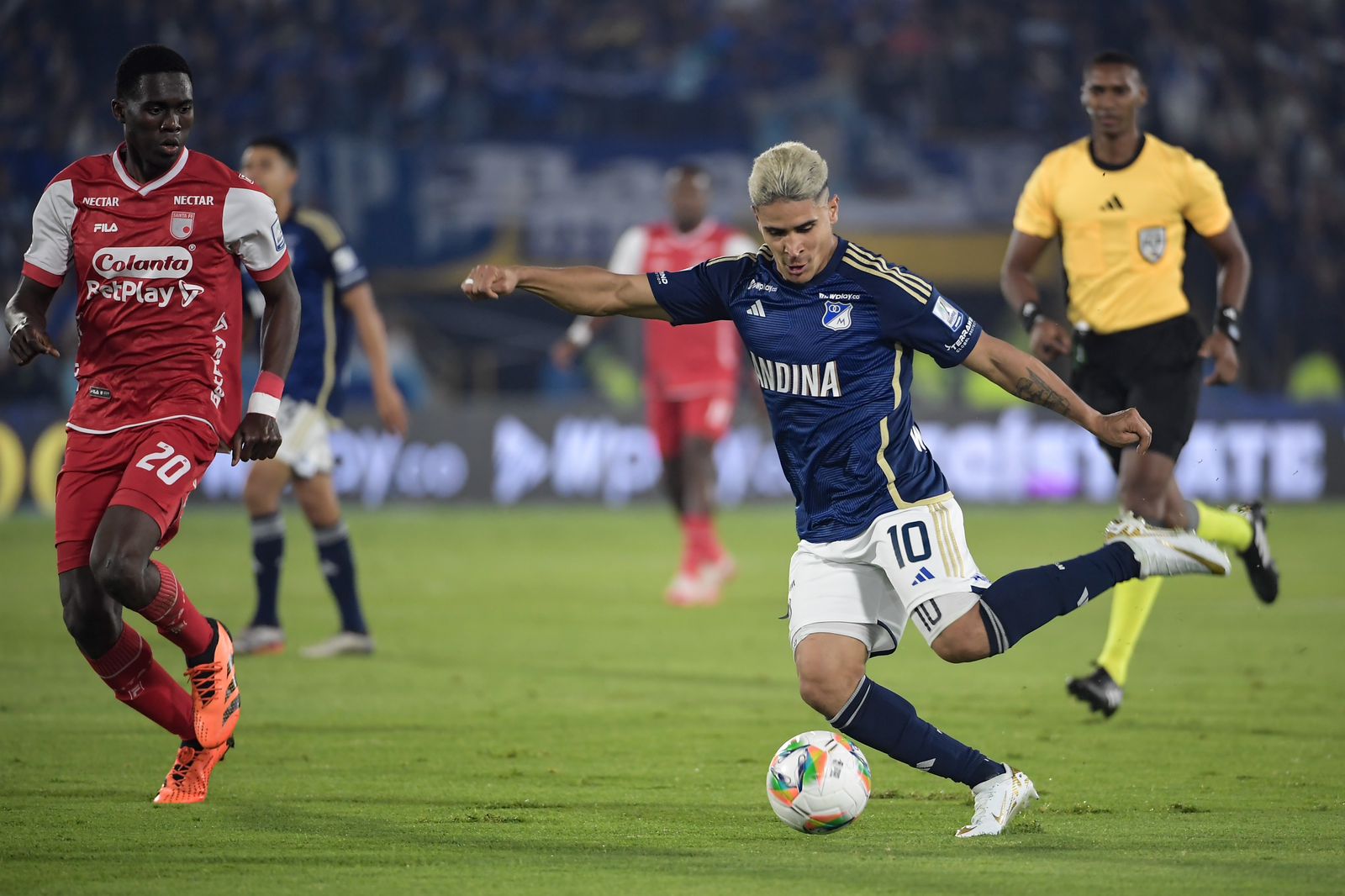 Daniel Cataño, de Millonarios, conduce la pelota ante la marca de Yílmar Velázquez.