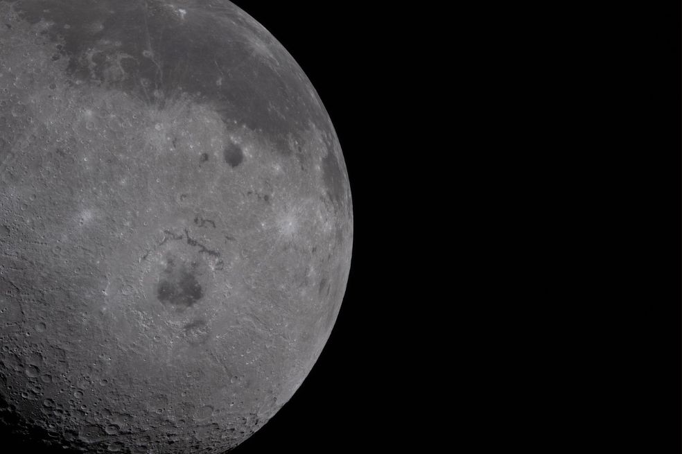 El lado visible, caracterizado por manchas oscuras de lava antigua, se aprecia en el tercio superior del disco lunar.