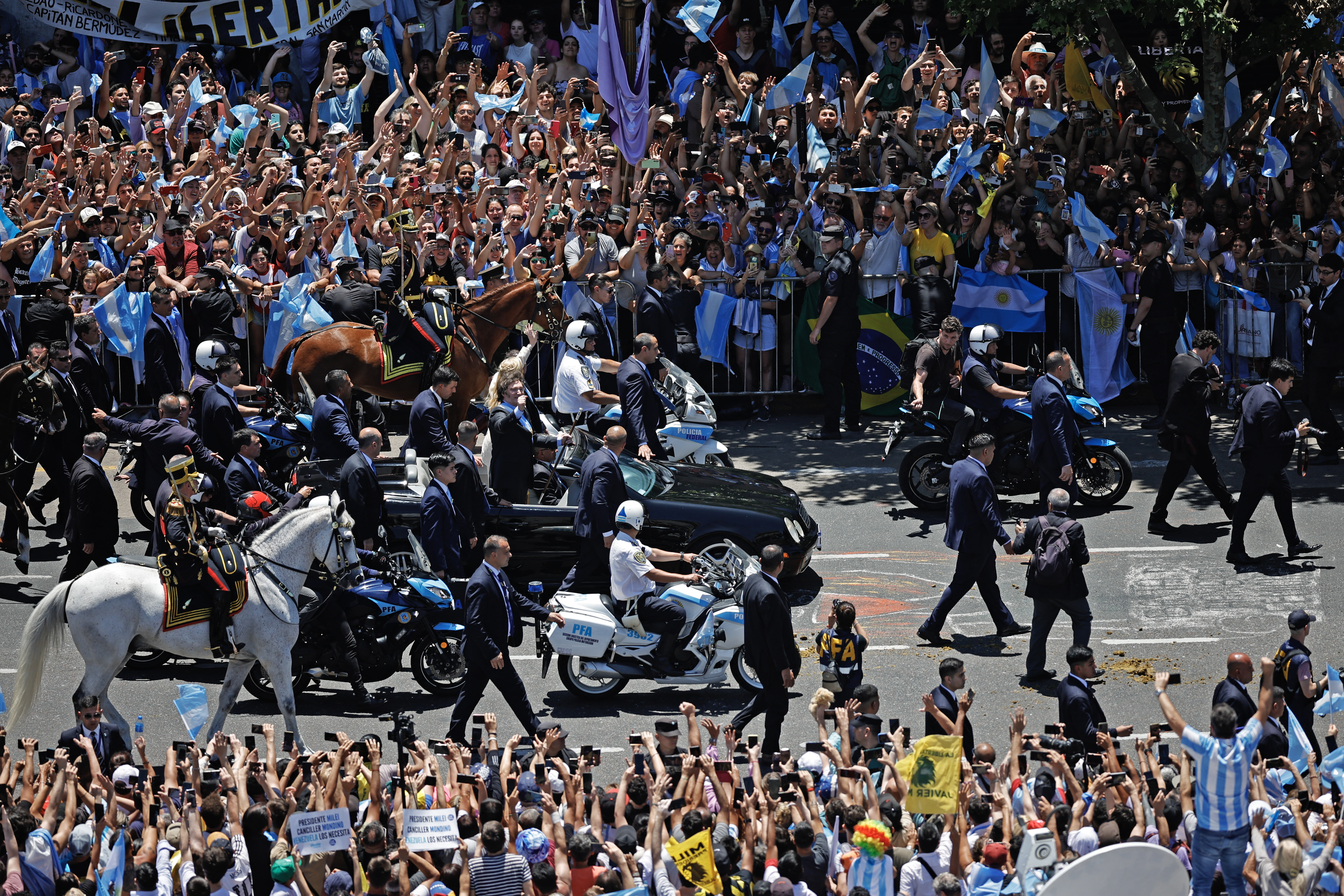 El nuevo presidente de Argentina, Javier Milei, saluda a sus seguidores mientras se dirige al Palacio Presidencial de la Casa Rosada después de prestar juramento durante una ceremonia de inauguración en el Congreso.
