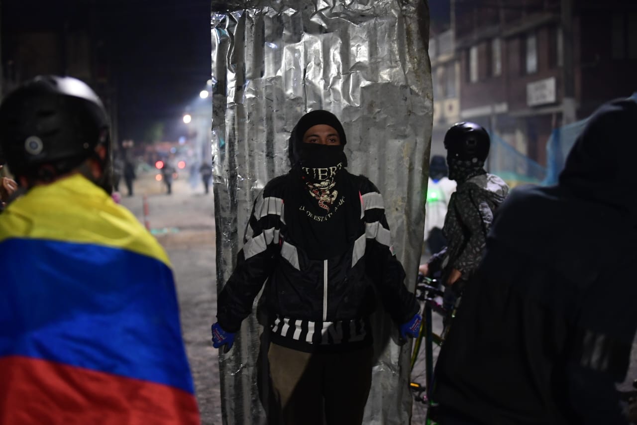 Un hombre encapuchado carga una teja de aluminio.