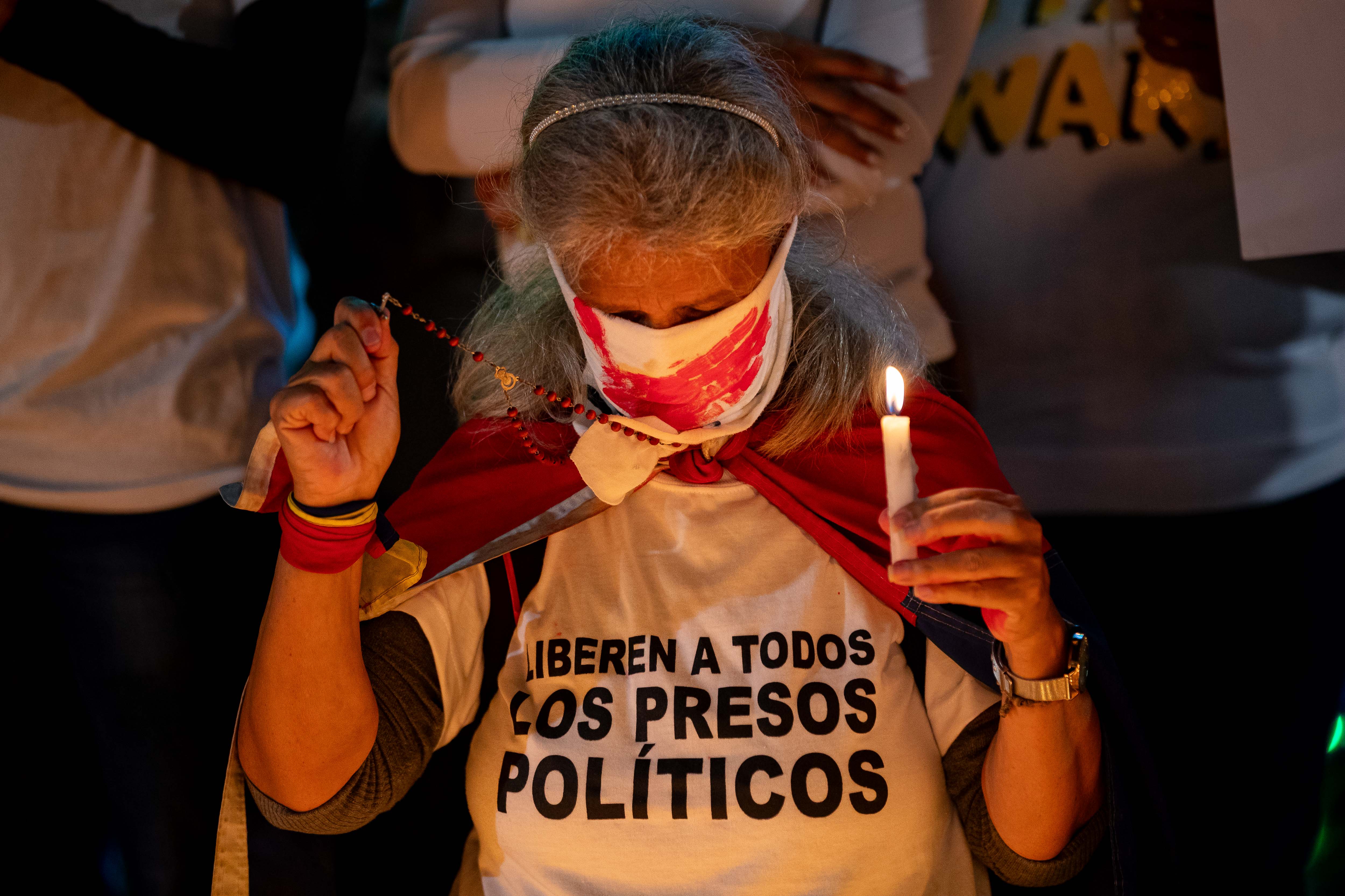 AME2587. CARACAS (VENEZUELA), 01/12/2024.- Una madre sostiene una vela y un rosario durante una vigilia este domingo, en Caracas (Venezuela). Familiares y amigos de los considerados "presos políticos", acompañados de activistas y otros ciudadanos, llevaron a cabo una vigilia en una plaza de Caracas para exigir la liberación de estos detenidos, así como el "cese de la represión" en el país. EFE/ Ronald Peña