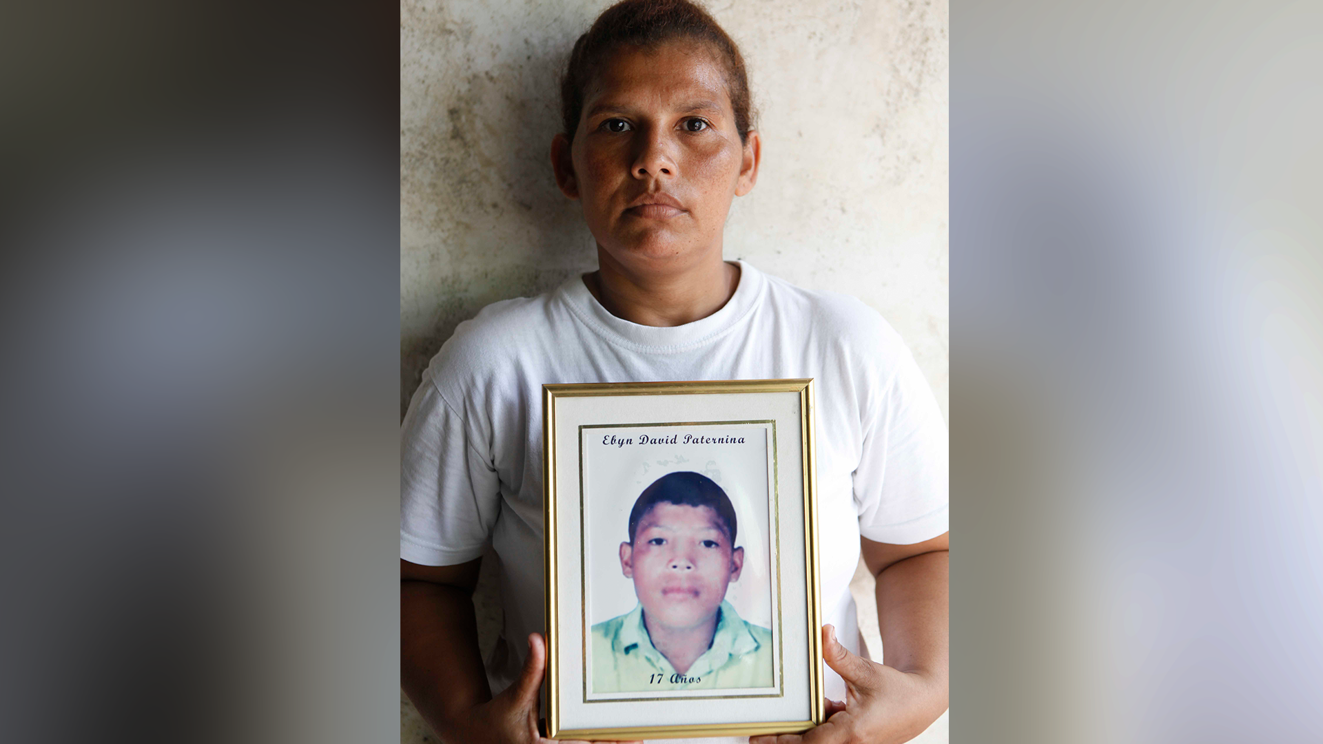 En los últimos 14 años, Ada Paternina, madre de Evin David, ha recorrido junto a su madre Sara del Socorro Parra y su hermano Carlos al menos cinco municipios en busca del cuerpo de su hijo. En la foto, tomada hace nueve años, Ada sostiene el retrato que la ha acompañado en la búsqueda de su hijo.