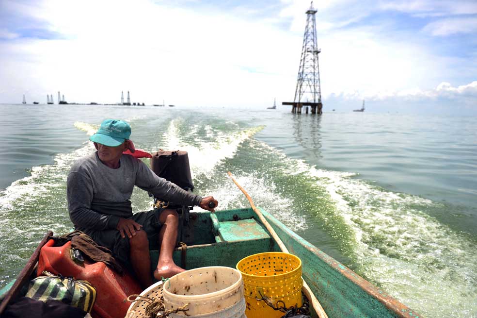 Un pescador navega frente a una torre petrolera del lago de Maracaibo , en el estado de Zulia. / AFP