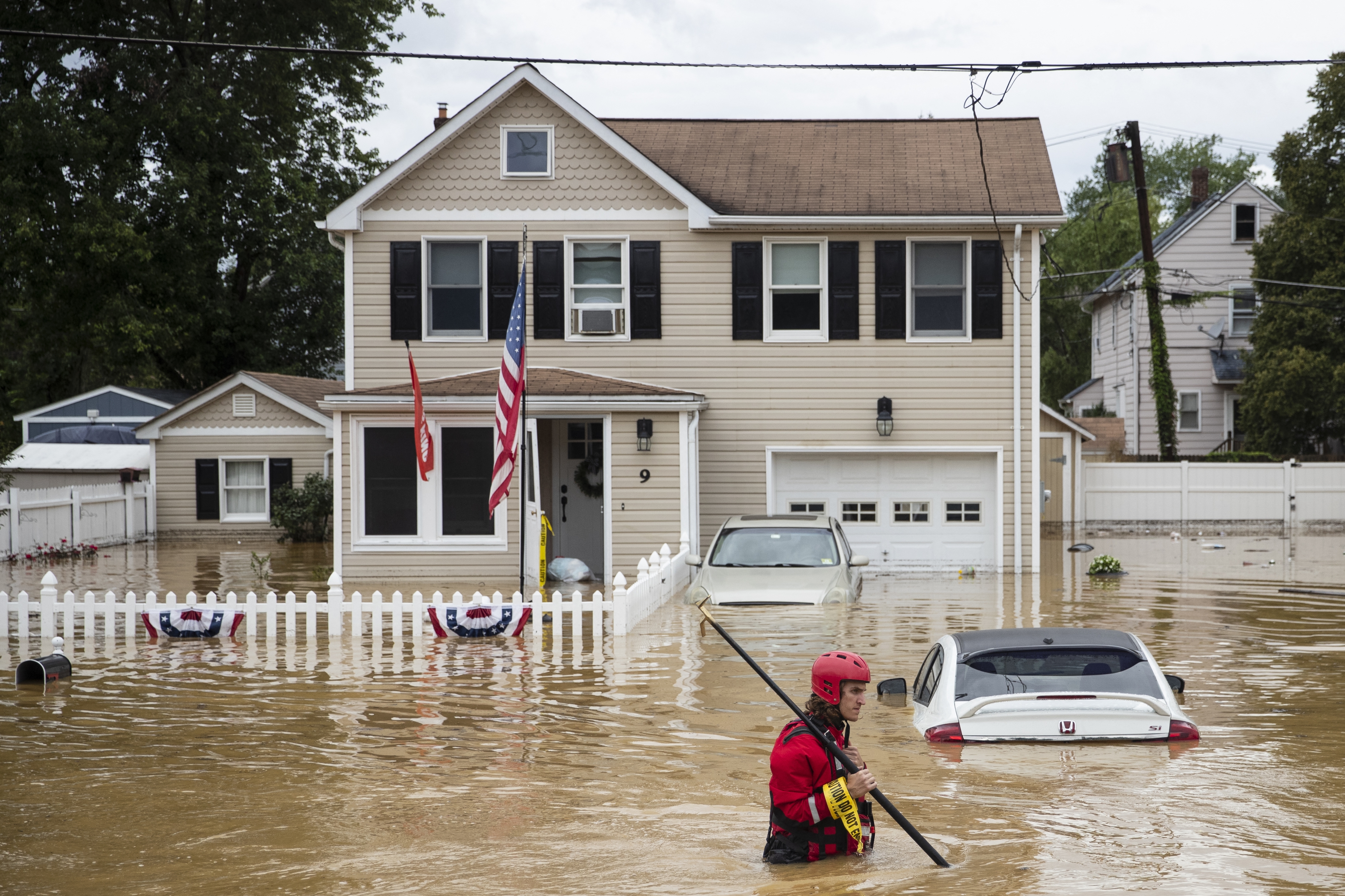 A New Market Volunteer Fire Company rescue crew member wades through high waters following a flash flood, as Tropical Storm Henri makes landfall, in Helmetta, New Jersey, on August 22, 2021. - Tropical Storm Henri slammed into Rhode Island on the US east coast Sunday, knocking out power to thousands of Americans, canceling scores of flights and bringing record rainfall. The storm -- earlier downgraded from a Category 1 Hurricane -- hit land near the town of Westerly at approximately 12:15 PM (1615 GMT), the National Weather Service said.Henri is a rare tropical storm to hit America's northeastern seaboard and comes as the surface layer of oceans warms due to climate change. (Photo by Tom Brenner / AFP)