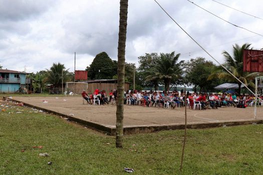 Esta fotografía, que está en poder de las autoridades, demostaría que la población civil de la vereda Alto Remanso sí estuvo retenida en el polideportivo. Como narran en sus testimonios, los habrían obligado a sentarse dando la espalda a la vereda y mirando hacia el río y la selva, según ellos, por alrededor de cuatro o cinco horas. En esta imagen se ve la presencia de menores de edad. Al fondo, casi sobre la orilla del río, se puede observar la presencia de dos militares.