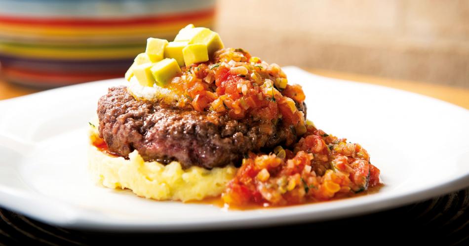 Hamburguesa sobre puré de papa y arracacha con salsa criolla