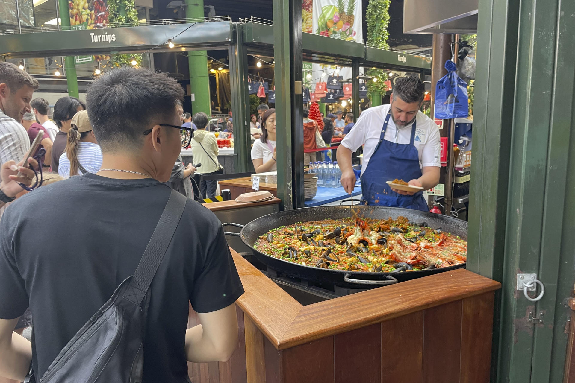 LONDRES, 23/07/2026.- El mercado gastronómico de Borough, uno de los más populares de Londres, recibe a diario largas colas de visitantes para comprar una porción de paella en el puesto de arroces que causa furor entre los turistas y visitantes y donde se venden más de 1.000 raciones a diario. Son las diez de la mañana y huele a aceite de oliva, ajo, cebolla, pimiento y tomate rallado, el tradicional sofrito de paella. También se escucha cómo las cucharas rascan el fondo de la paellera para obtener el característico 'socarrat'. Esta escena podría ser la típica imagen, salvando la hora, en cualquier restaurante, bar o calle del Mediterráneo español. Sin embargo, el lugar es el mercado gastronómico de Borough en Londres.-EFE/ Luis Campello