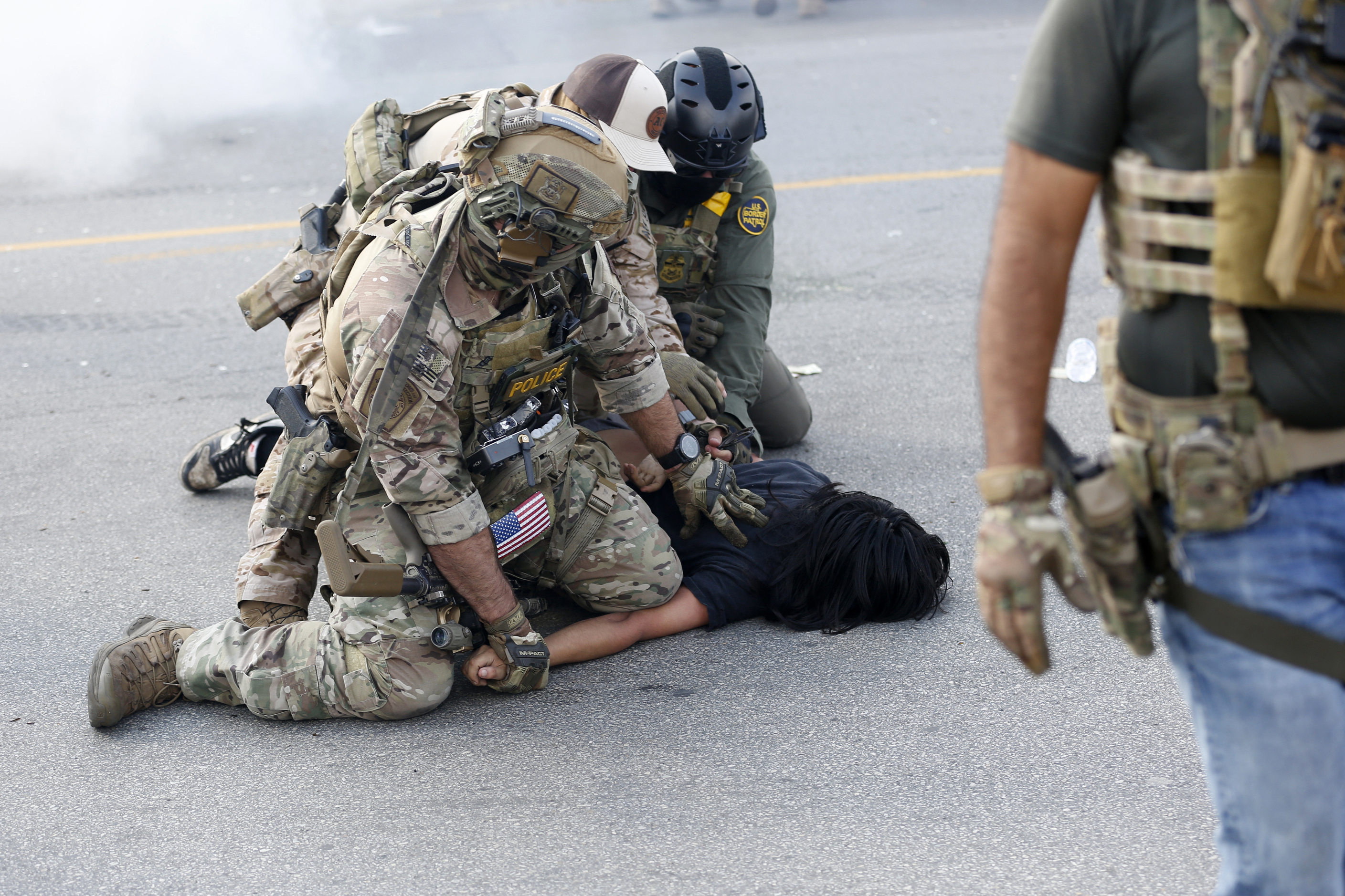 A person is detained as residents of Chicago's Brighton Park neighborhood confront US Border Patrol and other law enforcement agents at a gas station after Immigration and Customs Enforcement (ICE) agents allegedly detained an unidentified man riding in his car, in Chicago, Illinois, on October 4, 2025. US President Donald Trump, who campaigned on a pledge to deport large numbers of migrants, has encouraged authorities to be more aggressive as he seeks to hit his widely reported target of one million deportations annually. (Photo by OCTAVIO JONES / AFP)