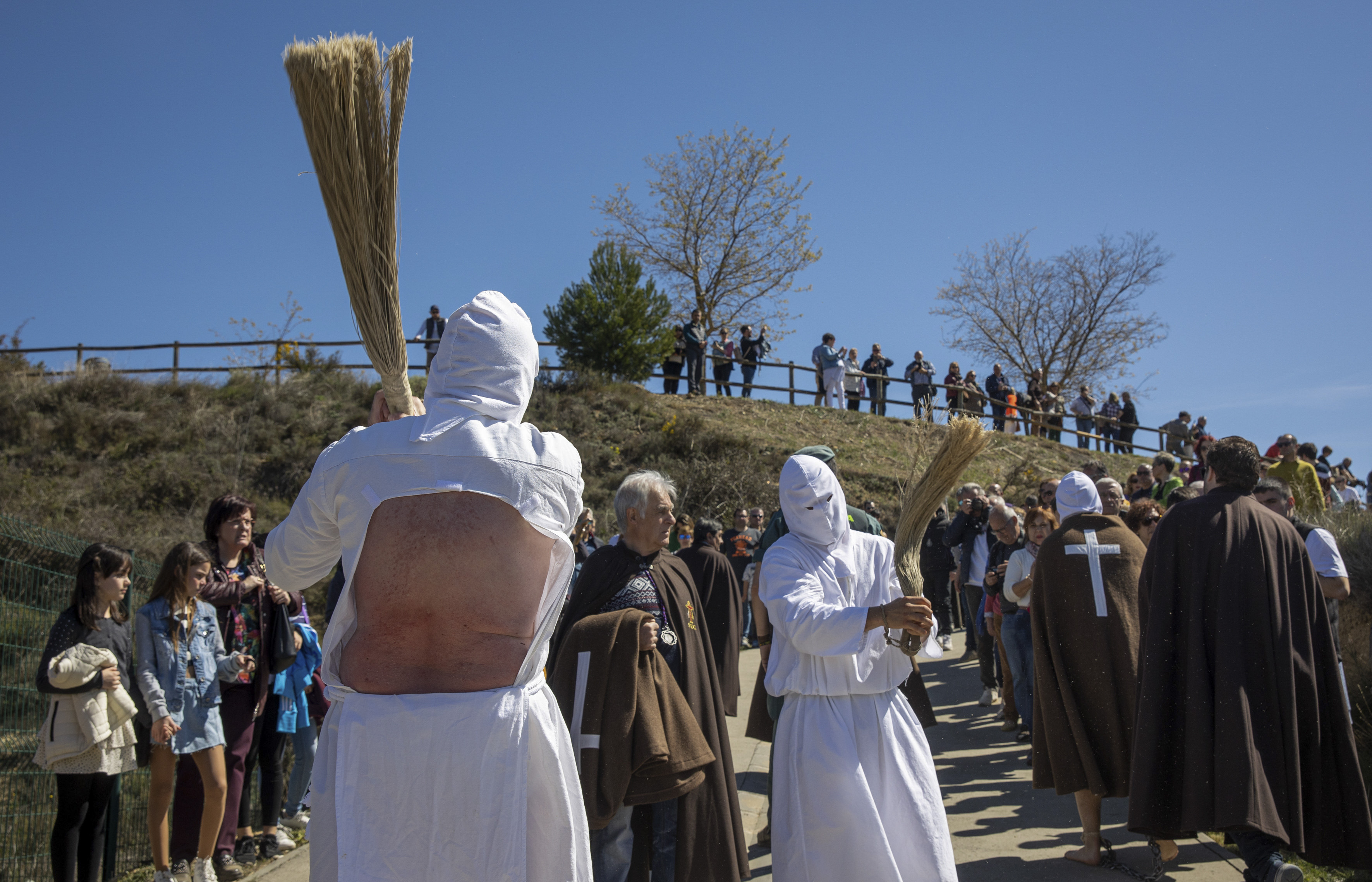 SAN VICENTE DE LA SONSIERRA 07/04/2023.- Un par de disciplinantes durante el Vía Crucis del municipio riojano de San Vicente de la Sonsierra, que acoge a los picaos, quienes, con el rosto cubierto, flagelan su espalda, donde se autogolpean entre 800 y 1.000 veces con una madeja para, después, ser pinchados 12 veces con una "esponja" de cera virgen repujada de cristales y curar sus heridas con agua de romero.- EFE/ Raquel Manzanares