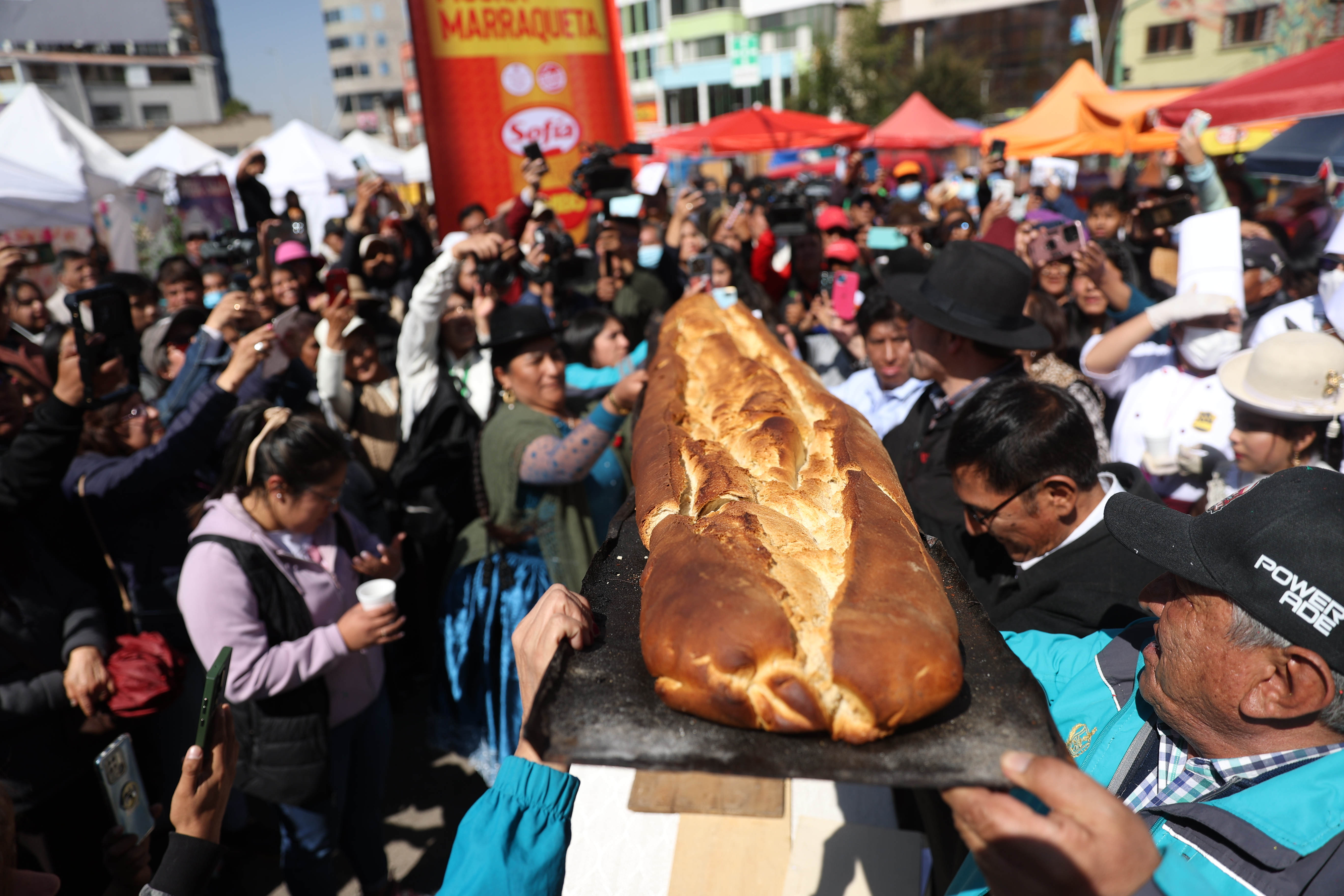 -FOTODELDÍA- AME9880. LA PAZ (BOLIVIA), 06/07/2024.- Ciudadanos paceños participan durante el día de la "marraqueta" este sábado en La Paz (Bolivia). Crujiente por fuera y suave y aireada por dentro, así es la emblemática marraqueta de más de tres metros que se elabora en la ciudad boliviana de La Paz y que fue homenajeada este sábado con la presentación de un 'pan de batalla', como también se conoce al alimento en Bolivia. EFE/Luis Gandarillas
