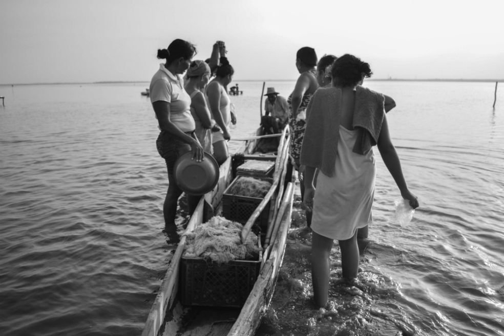 Las lavanderas rodean la canoa para comprar pescado.