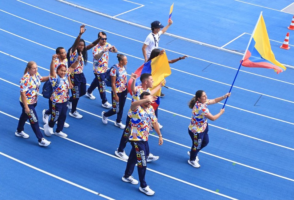 Arenas alzando la bandera de Colombia junto a sus deportistas.