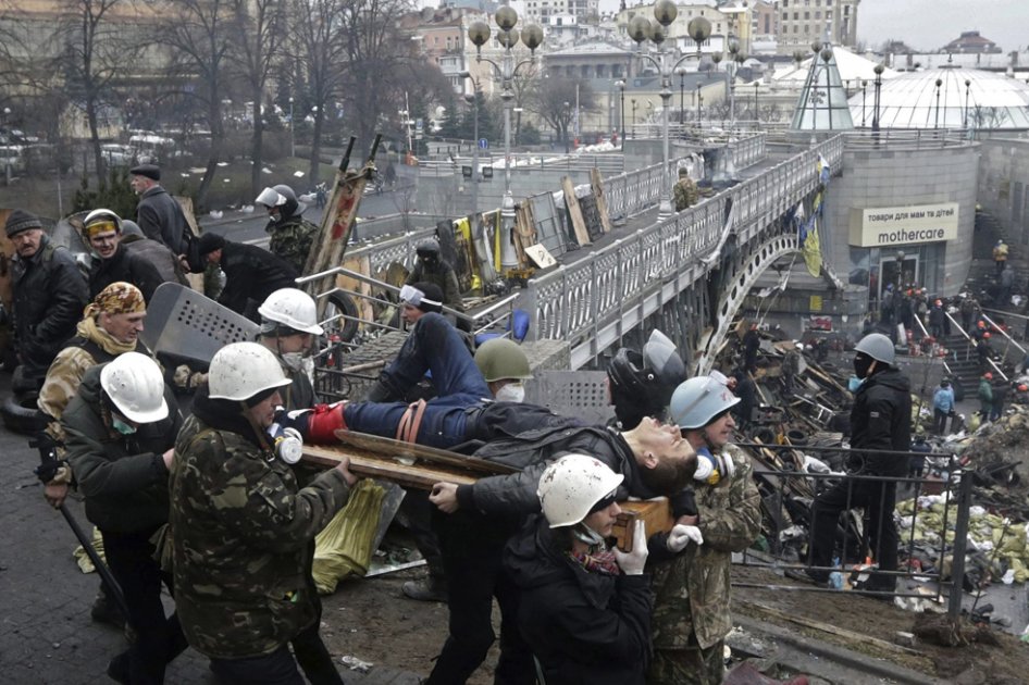Manifestantes trasladan a un compañero herido durante los enfrentamientos con los antidisturbios en la Plaza de la Independencia en Kiev