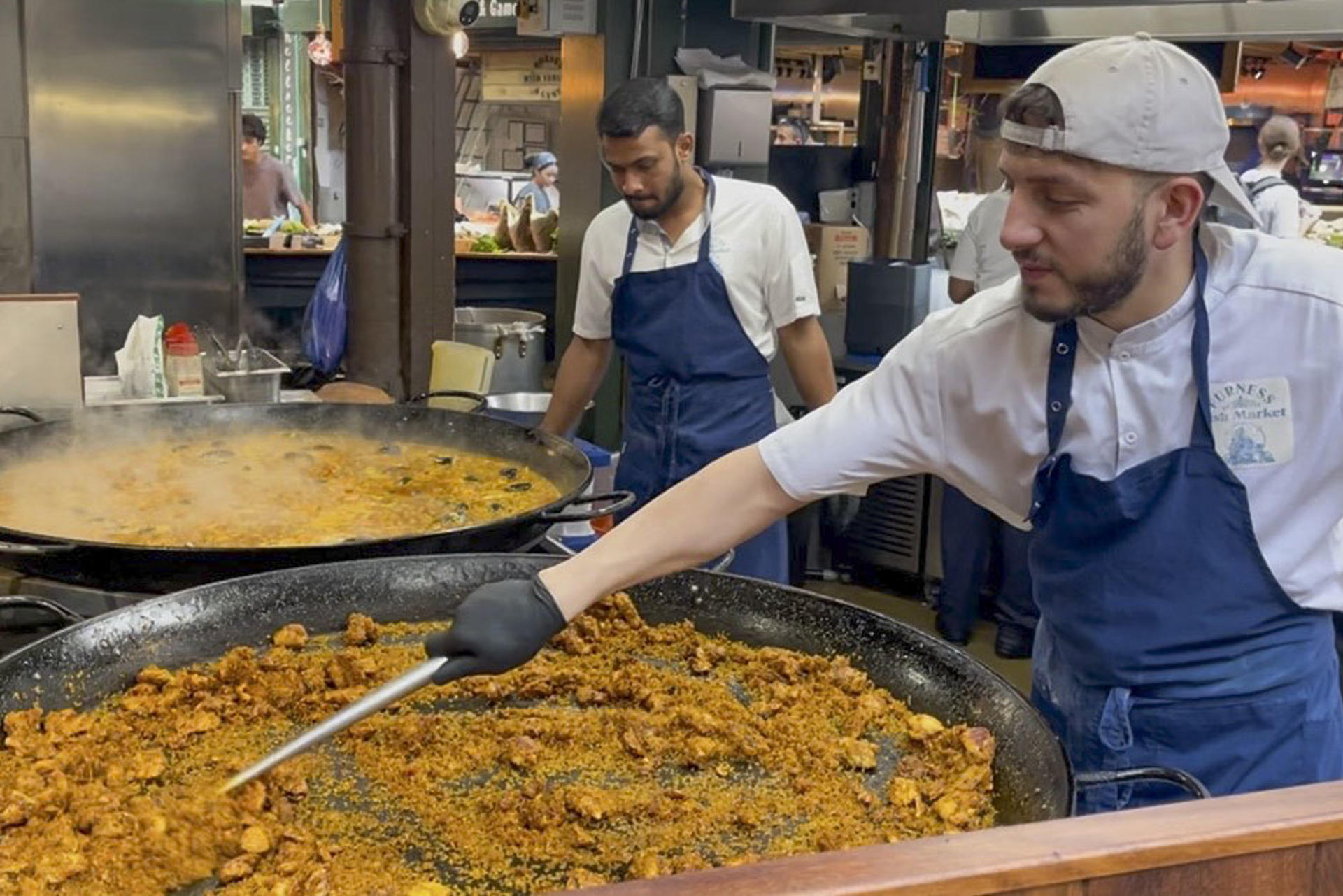 LONDRES, 23/07/2026.- El mercado gastronómico de Borough, uno de los más populares de Londres, recibe a diario largas colas de visitantes para comprar una porción de paella en el puesto de arroces que causa furor entre los turistas y visitantes y donde se venden más de 1.000 raciones a diario. Son las diez de la mañana y huele a aceite de oliva, ajo, cebolla, pimiento y tomate rallado, el tradicional sofrito de paella. También se escucha cómo las cucharas rascan el fondo de la paellera para obtener el característico 'socarrat'. Esta escena podría ser la típica imagen, salvando la hora, en cualquier restaurante, bar o calle del Mediterráneo español. Sin embargo, el lugar es el mercado gastronómico de Borough en Londres.-EFE/ Luis Campello