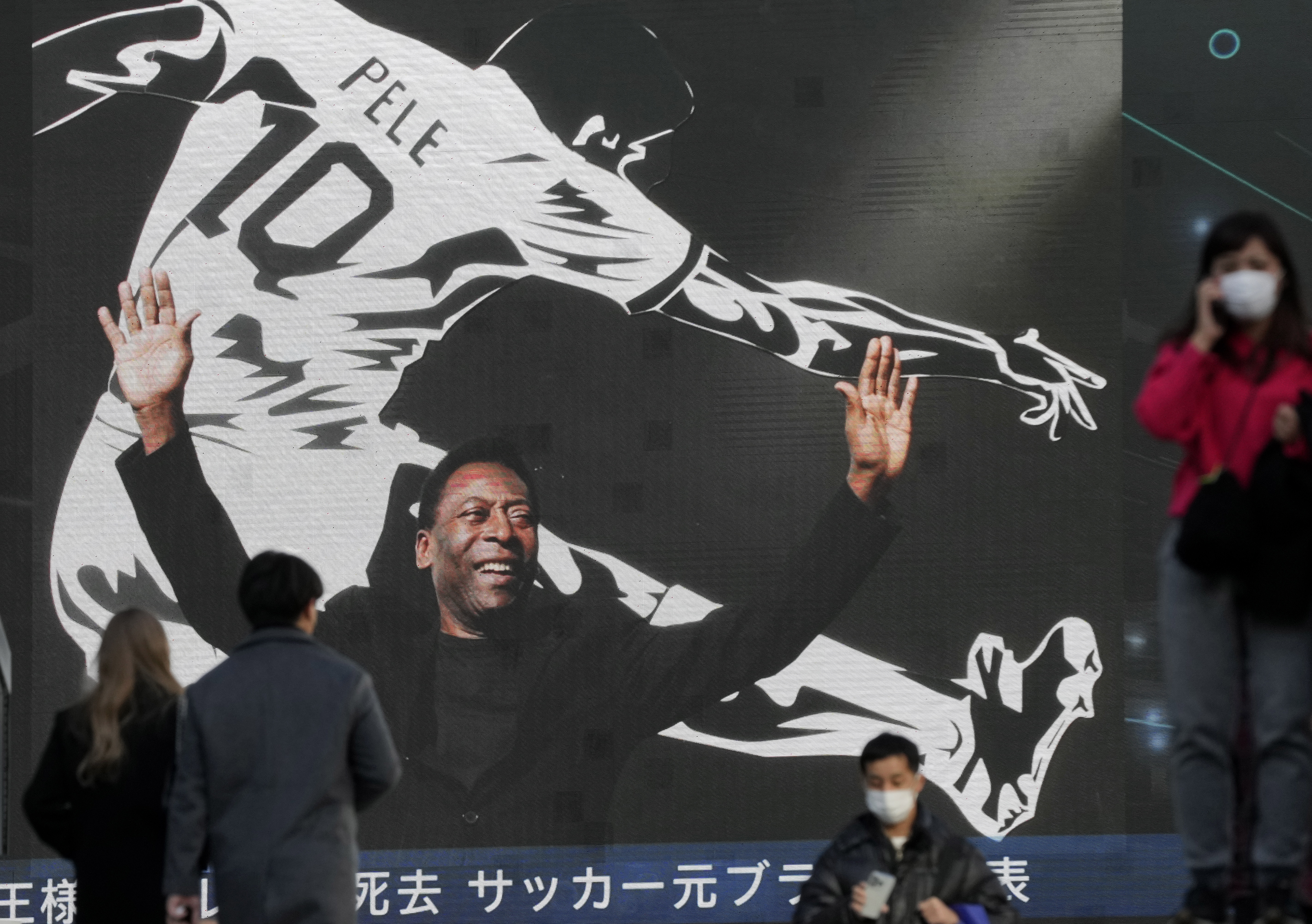 -FOTODELDIA- Tokio (Japón), 30/12/2022.- Varias personas caminan junto a una pantalla gigante que anuncia la muerte de Edson Arantes do Nascimento 'Pelé', para muchos el rey del fútbol, en las calles de Tokio, Japón este viernes. EFE/ Kimimasa Mayama