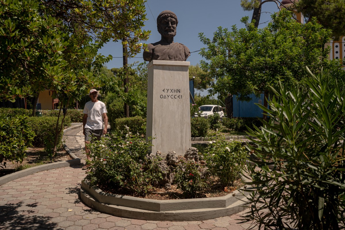 A man walks next to a bust of Odysseus in the central square of the village of Stavros, on the island of Ithaca, in the Ionian Sea, on August 3, 2026.
