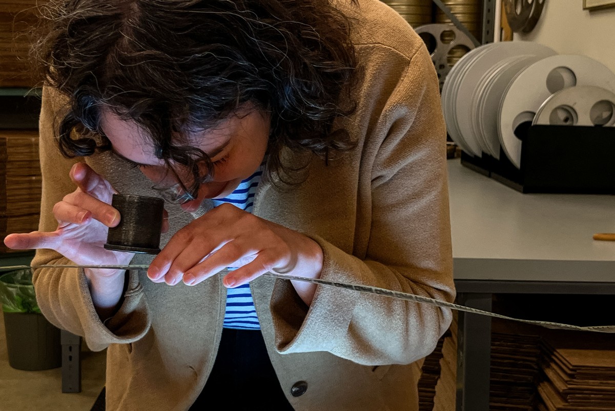 La técnica de la bóveda de películas de nitrato, Courtney Holschuh, utilizando una lupa, observa la película original del cortometraje mudo francés de Georges Méliès de 1897, "Gugusse et l'Automate", en un espacio de trabajo en la bóveda de películas de nitrato en el Campus Packard de la Biblioteca del Congreso. Conservación Audiovisual Nacional