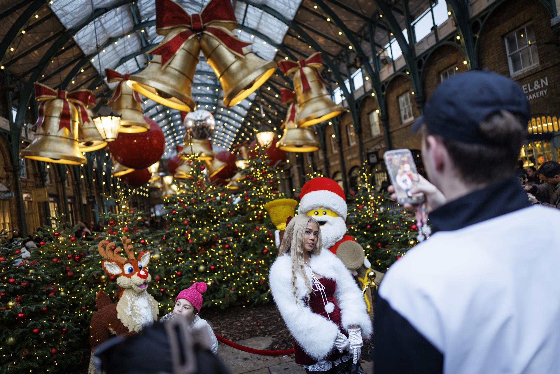 LONDON (United Kingdom), 22/12/2025.- A person wearing a Christmas themed outfit poses for a picture at Covent Garden Market as people do their Christmas shopping amid festive decorations in London, Britain, 22 December 2025. (Reino Unido, Londres) EFE/EPA/TOLGA AKMEN