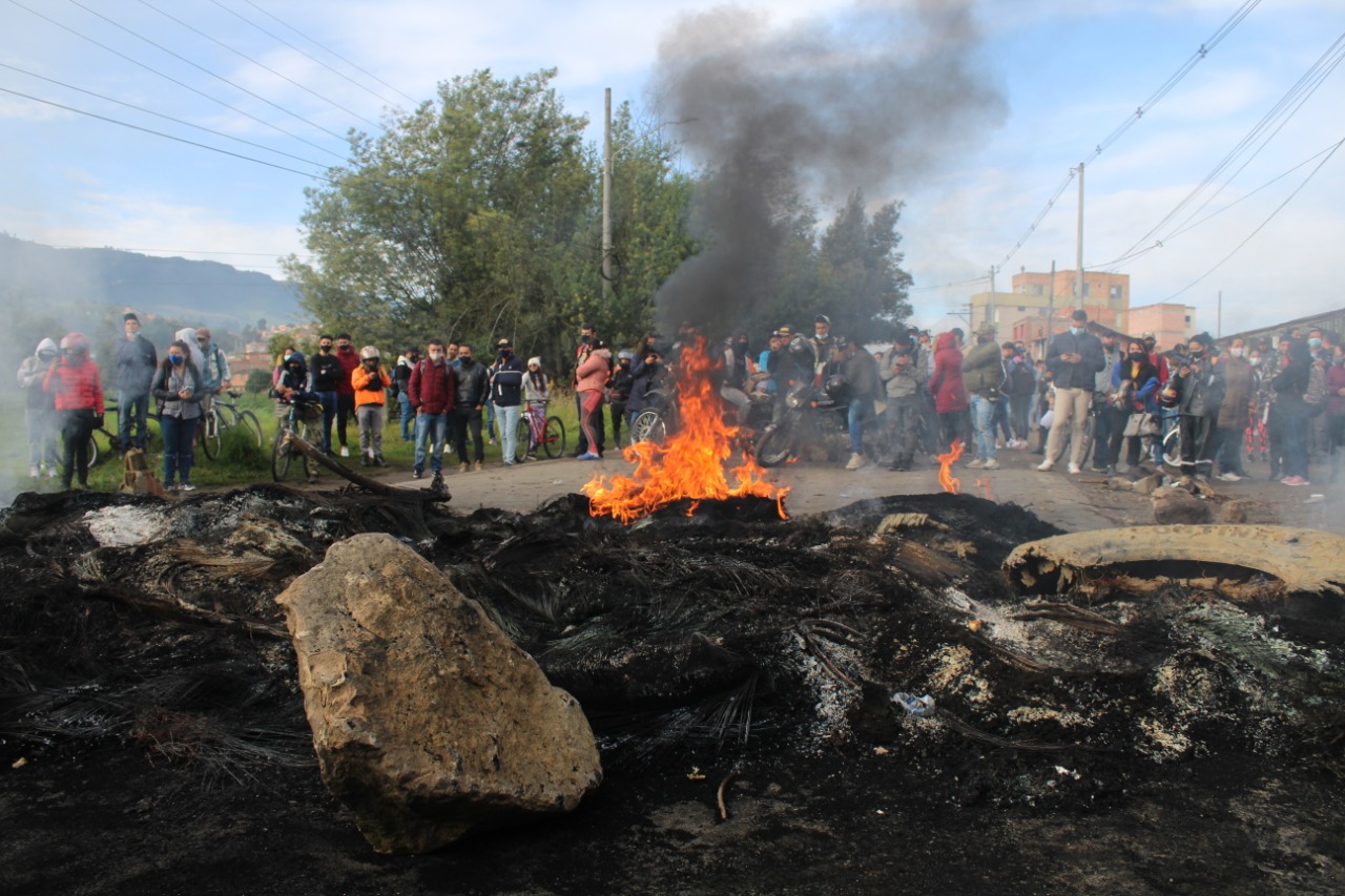 Varias personas ven desde lejos una barricada en llamas