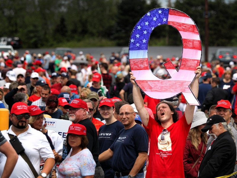 Un hombre sostiene un cartel con la Q de QAnon, el grupo conspiracionista.