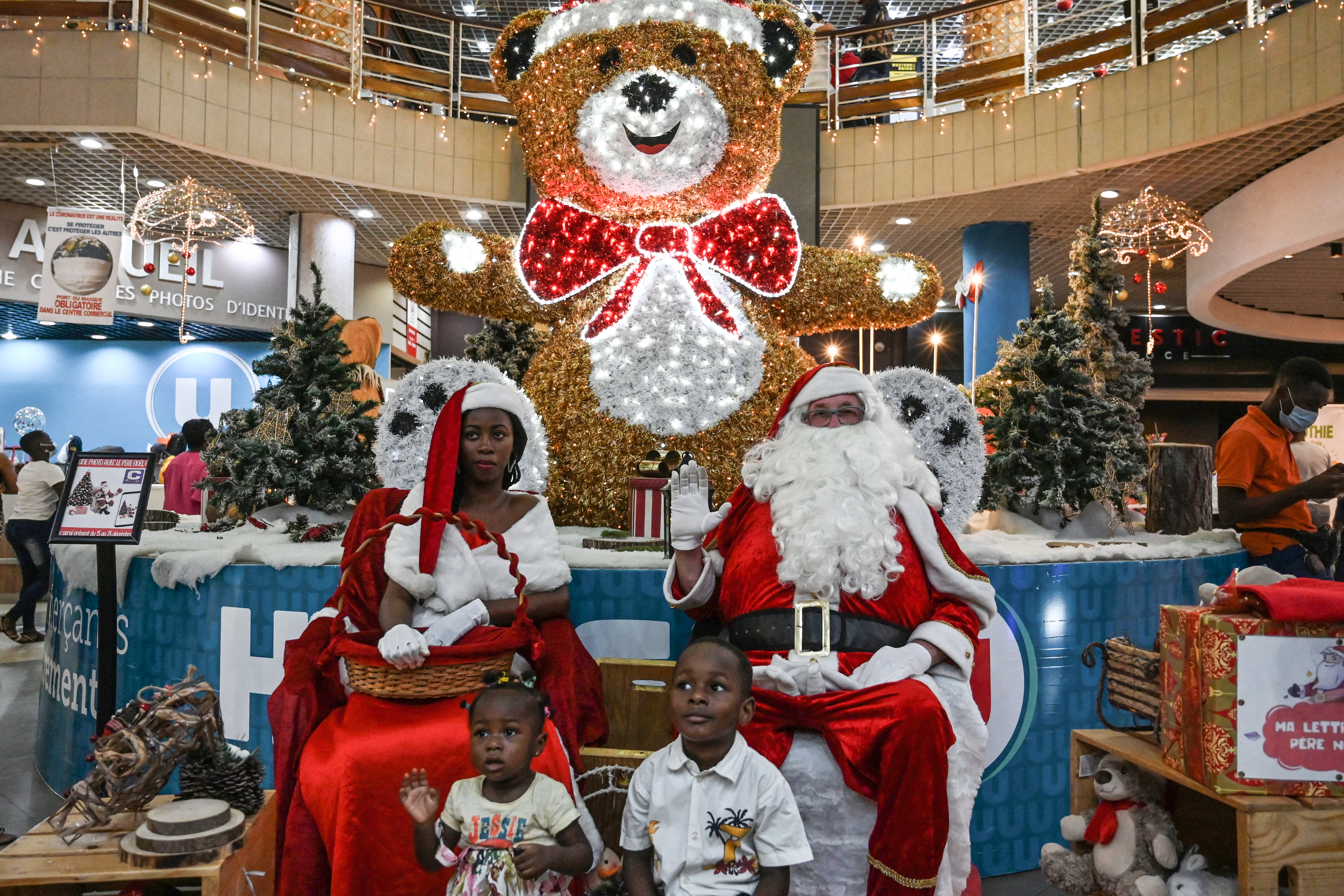 Costa de Marfil: Un hombre y una mujer vestidos de Santa Claus posan para una foto con niños en el pasillo de un supermercado en Abidjan.