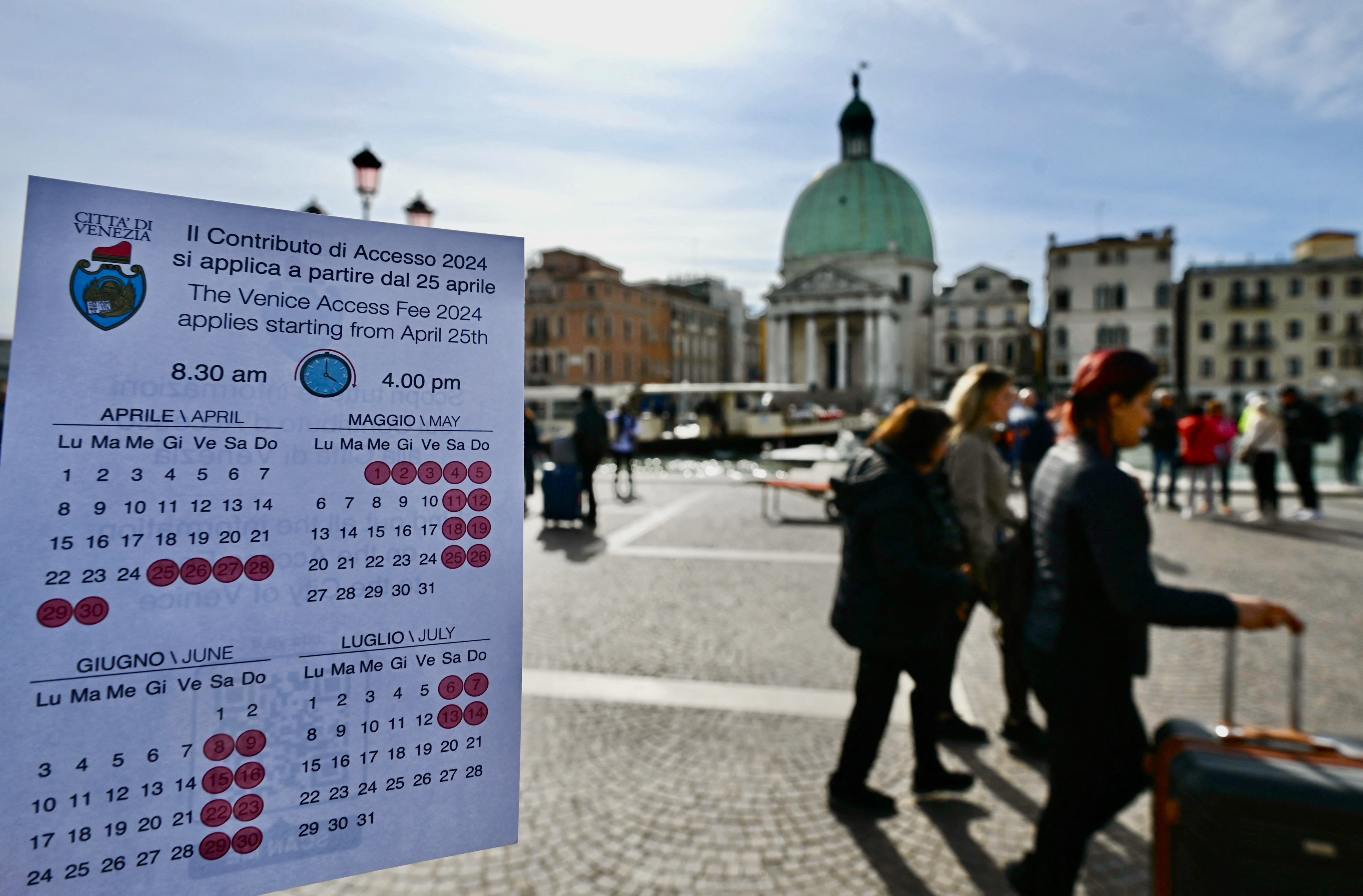 A person shows a calendar of the paying days to visit Venice, on April 19, 2024 in front of Santa Lucia train station in Venice.