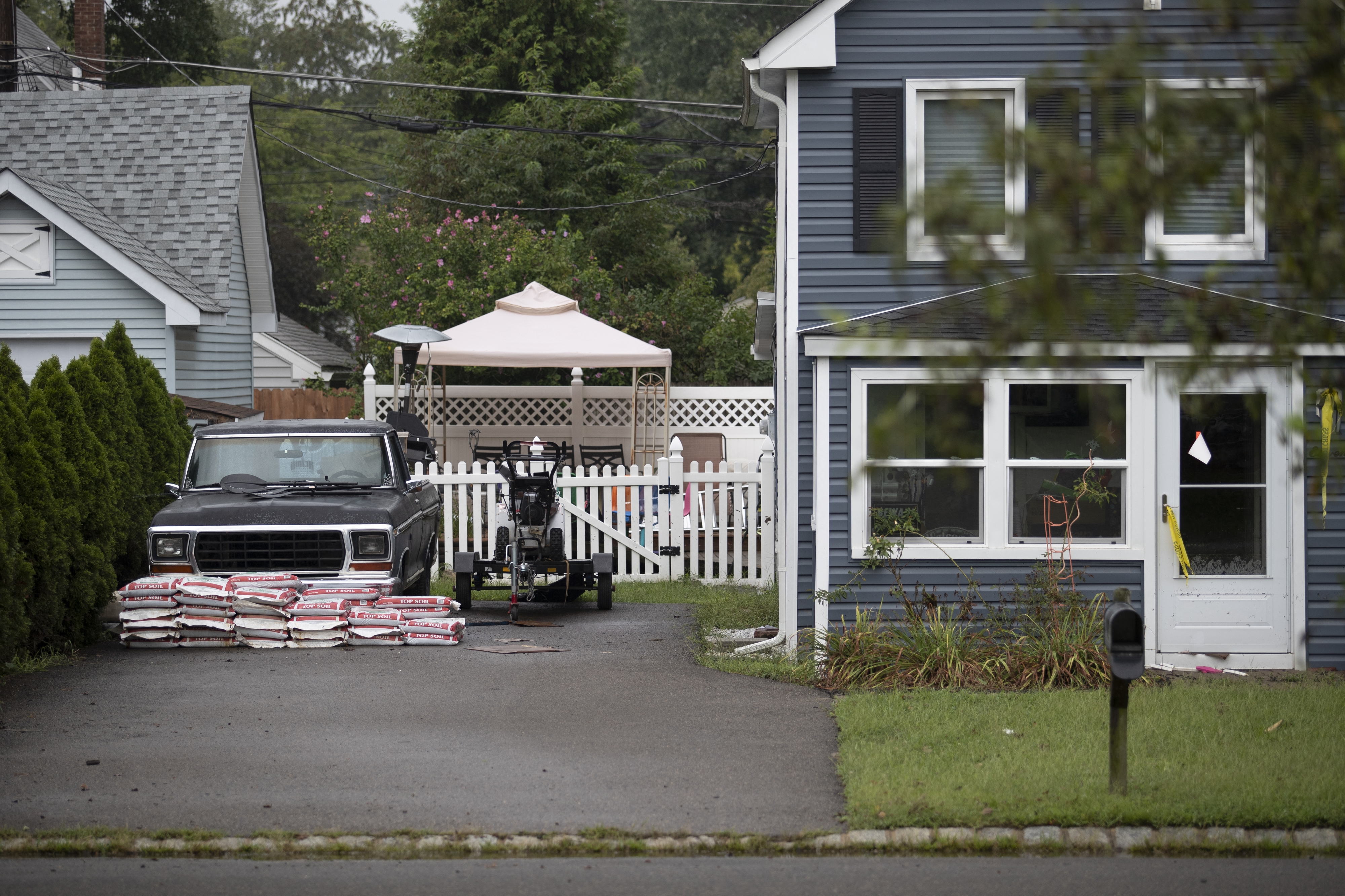 Top soil bags are stacked protectively beside a pickup truck beside a marked vacant home following Tropical Storm Henri�s landfall, in Helmetta, New Jersey, on August 23, 2021. - Tropical Storm Henri was downgraded to a tropical depression late August 22, 2021after slamming into Rhode Island on the US east coast, knocking out power to thousands of Americans, uprooting trees, and bringing record rainfall. The storm hit land near the town of Westerly, Rhode Island, at approximately 12:15 PM (1615 GMT), the National Weather Service said. Henri had already been downgraded from a Category 1 Hurricane earlier on Sunday.Millions of residents in New England and New York's Long Island had been told to prepare for violent winds, days without electricity, and storm surges of up to five feet. (Photo by Tom Brenner / AFP)