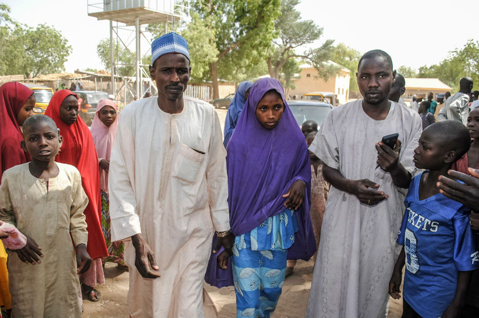 Una de las niñas liberadas por Boko Haram camina junto a su padre (izquierda) de regreso a su casa. / AFP